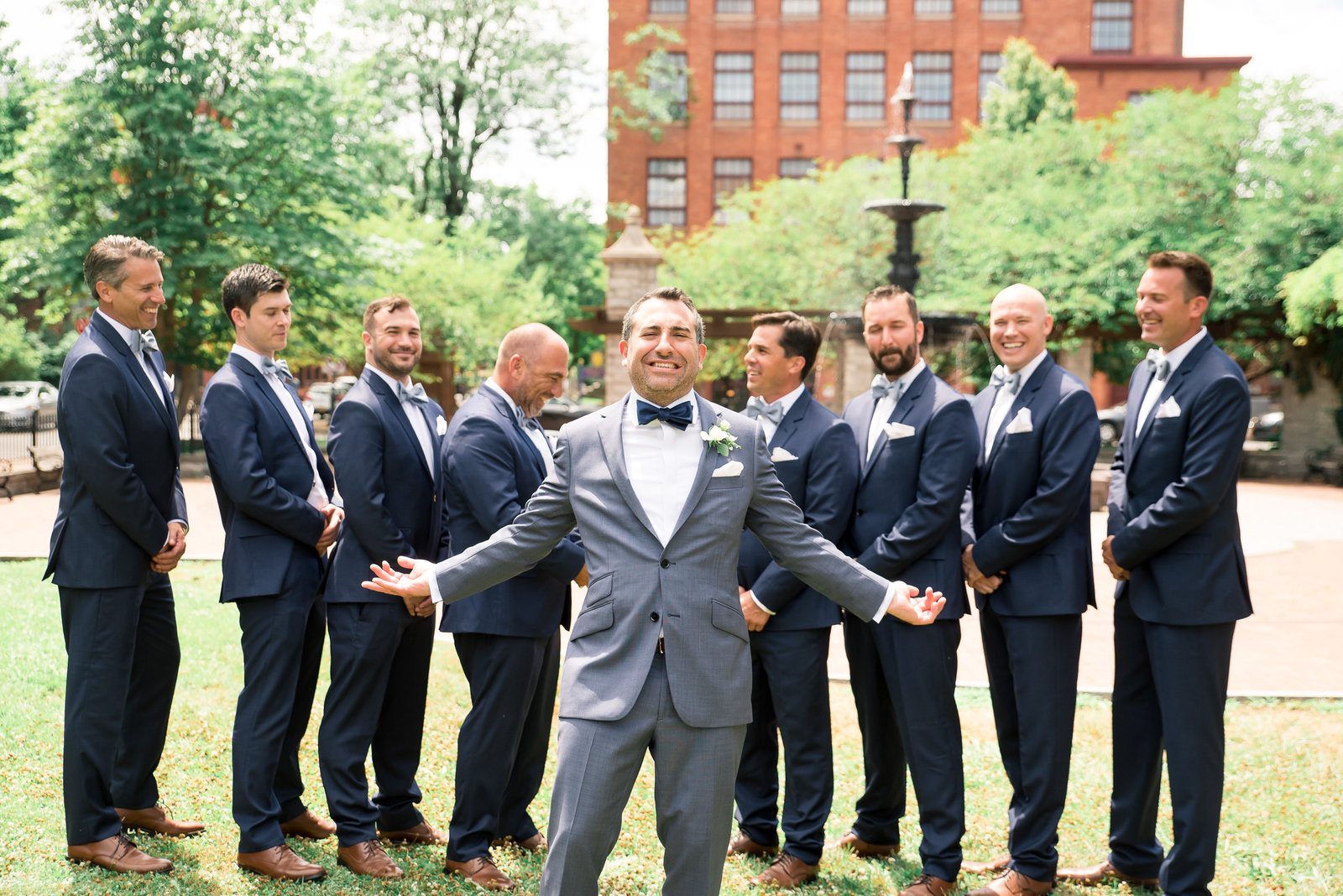 Groomsmen pose for a silly picture in front of a fountain in Armory Square. Syracuse Photographer