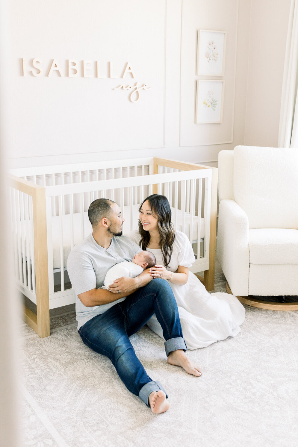 Image of new parents holding newborn baby sitting in nursery taken by Sacramento Newborn Photographer Kelsey Krall