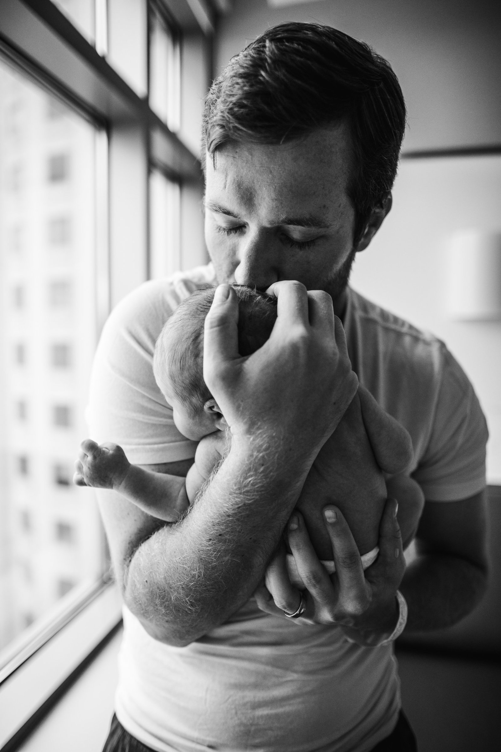dad cradles diaper clad newborn to chest during boston photo session