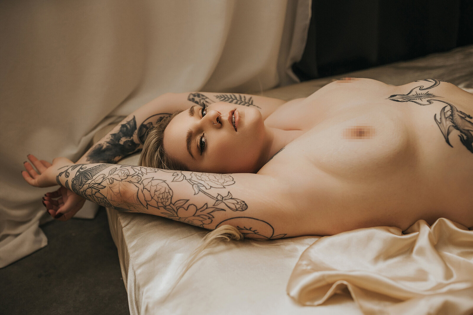 tattooed woman laying on bed in vancouver boudoir studio