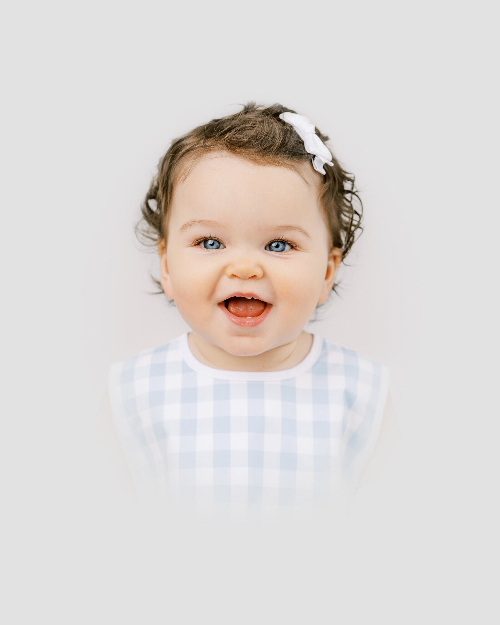Color heirloom portrait of baby girl smiling with dark curly hair and bright blue eyes by Worth Capturing