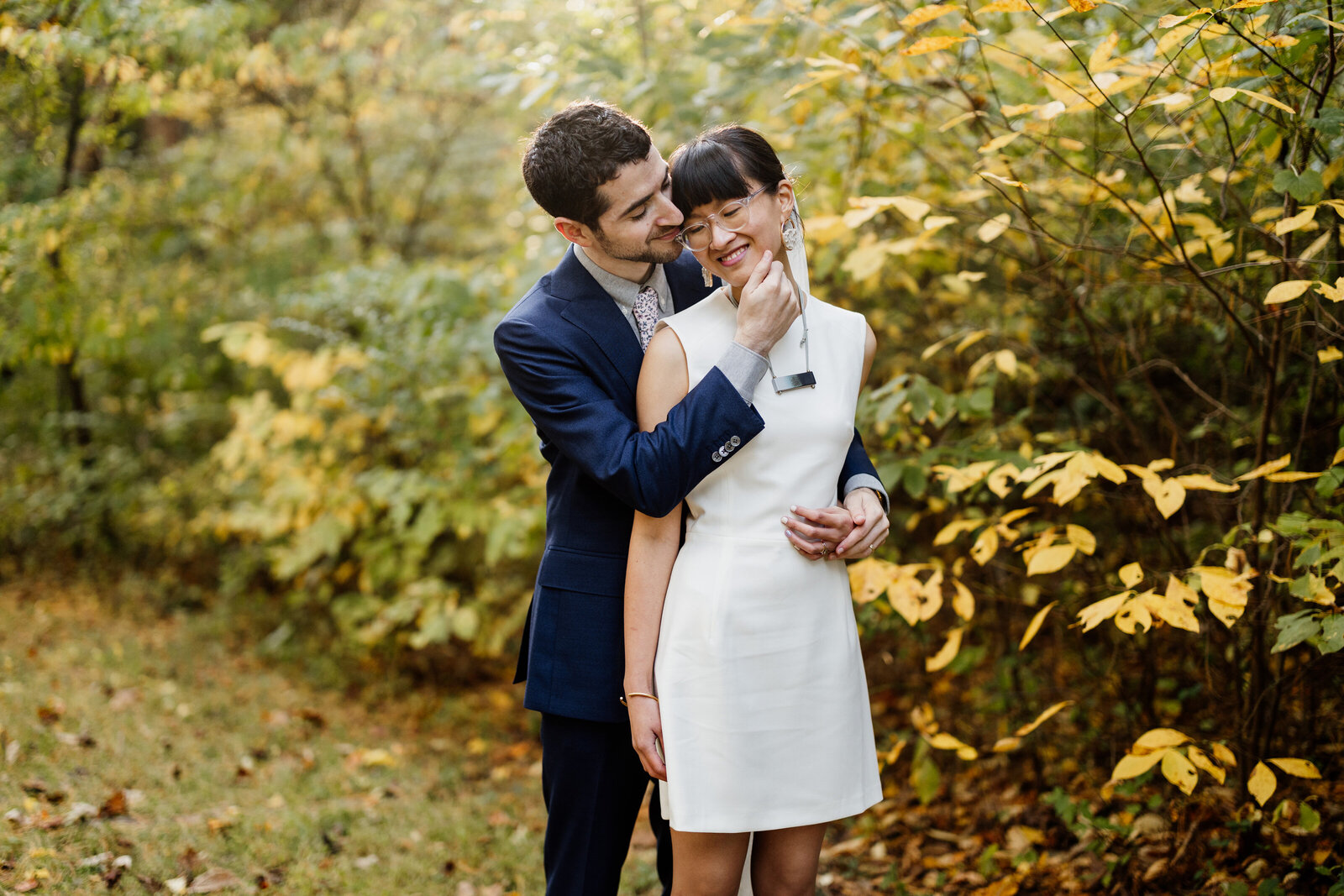 bride and groom hugging in fall leaves