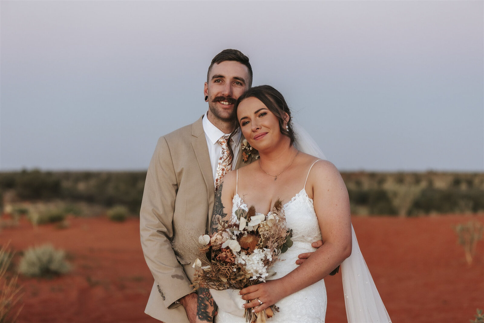 Uluru wedding showing a bride and a groom with a bouquet in the desert