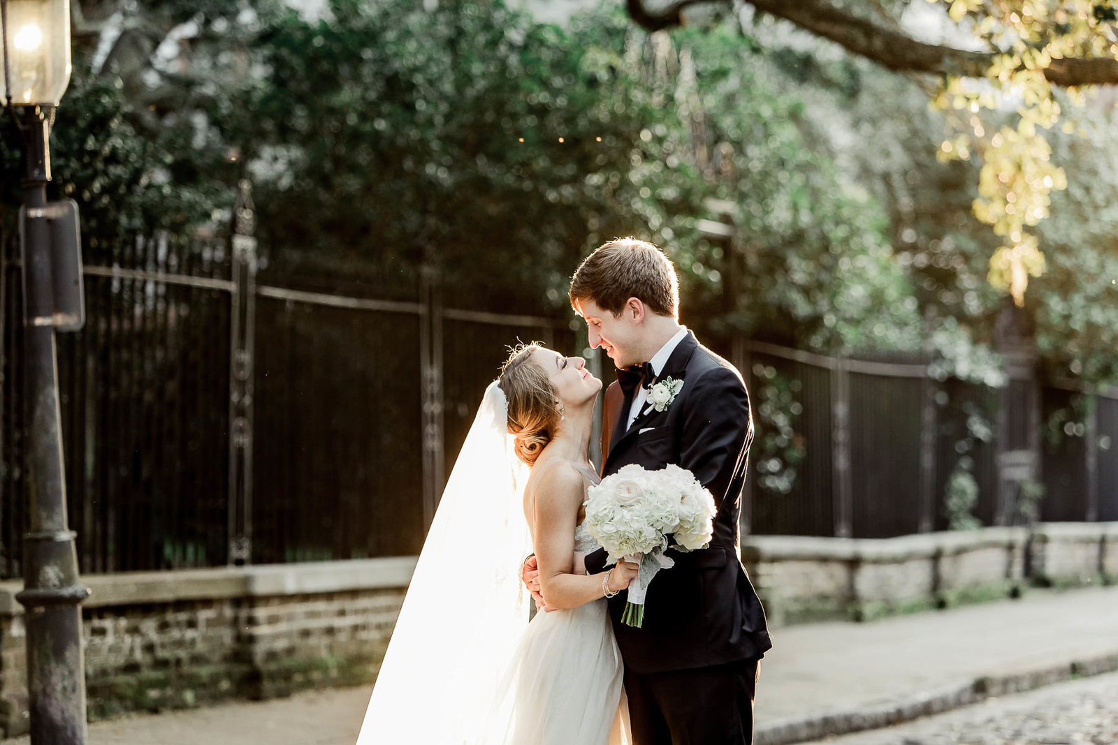 Bride and groom stand on the cobblestones of Washington Square, Charleston, South Carolina