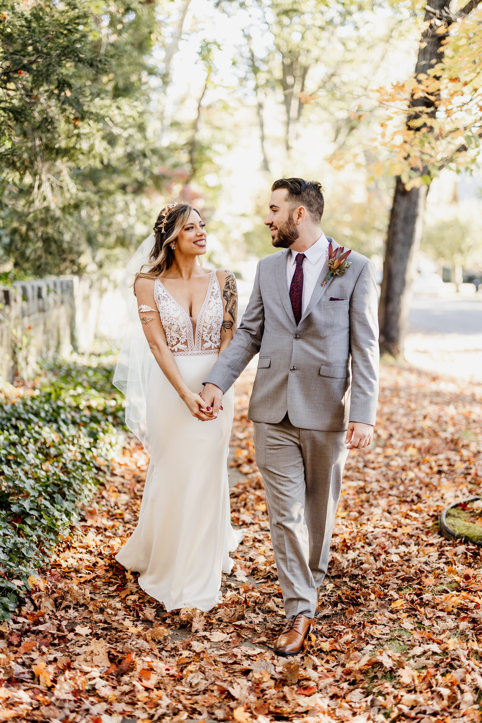 bride and groom walking in fall leaves