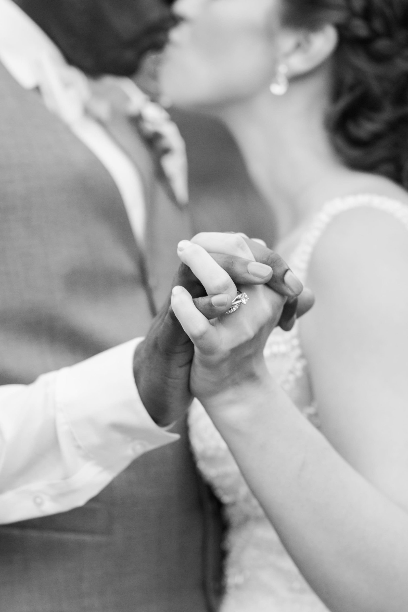 Bride and groom kissing and holding hands in black and white