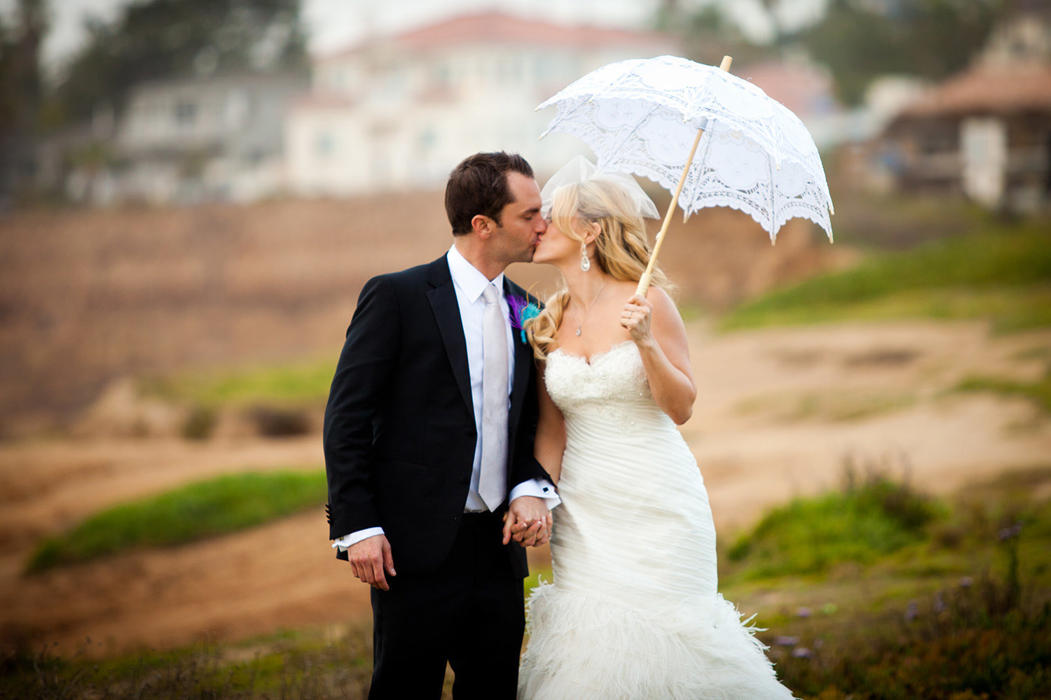bride and groom with umbrella at beach