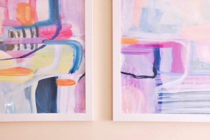 Two white framed pieces of colorful abstract art.