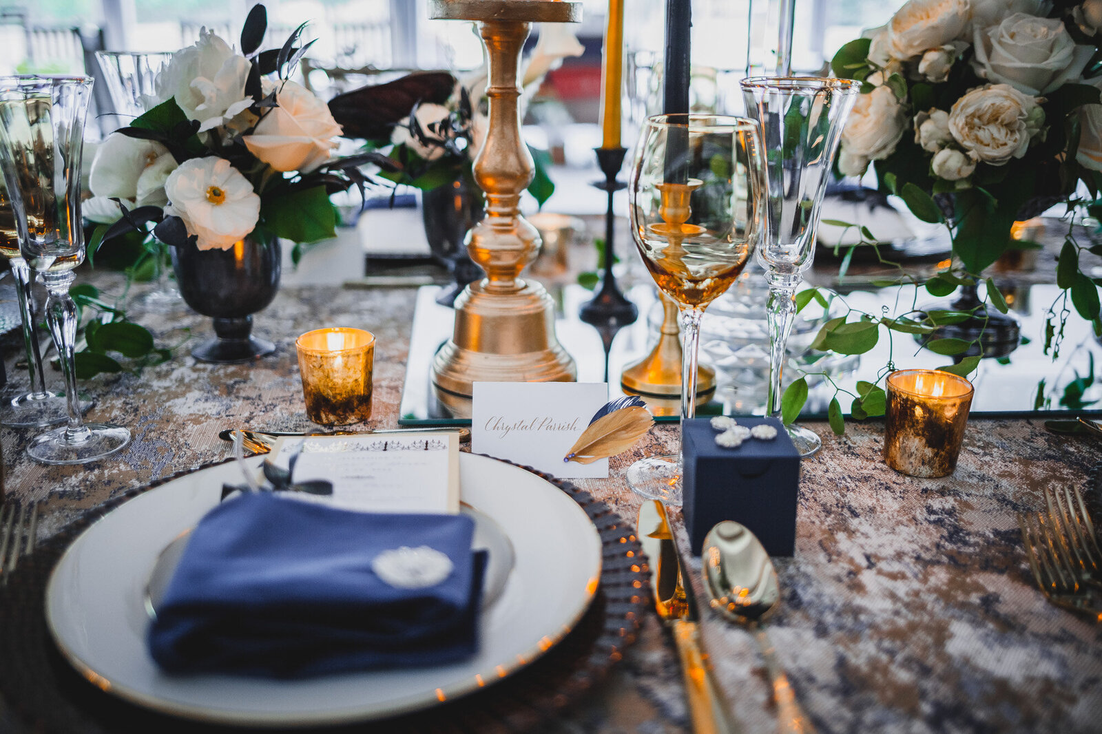 Wedding reception table that has dinnerwares, glasses, candles and floral centerpieces