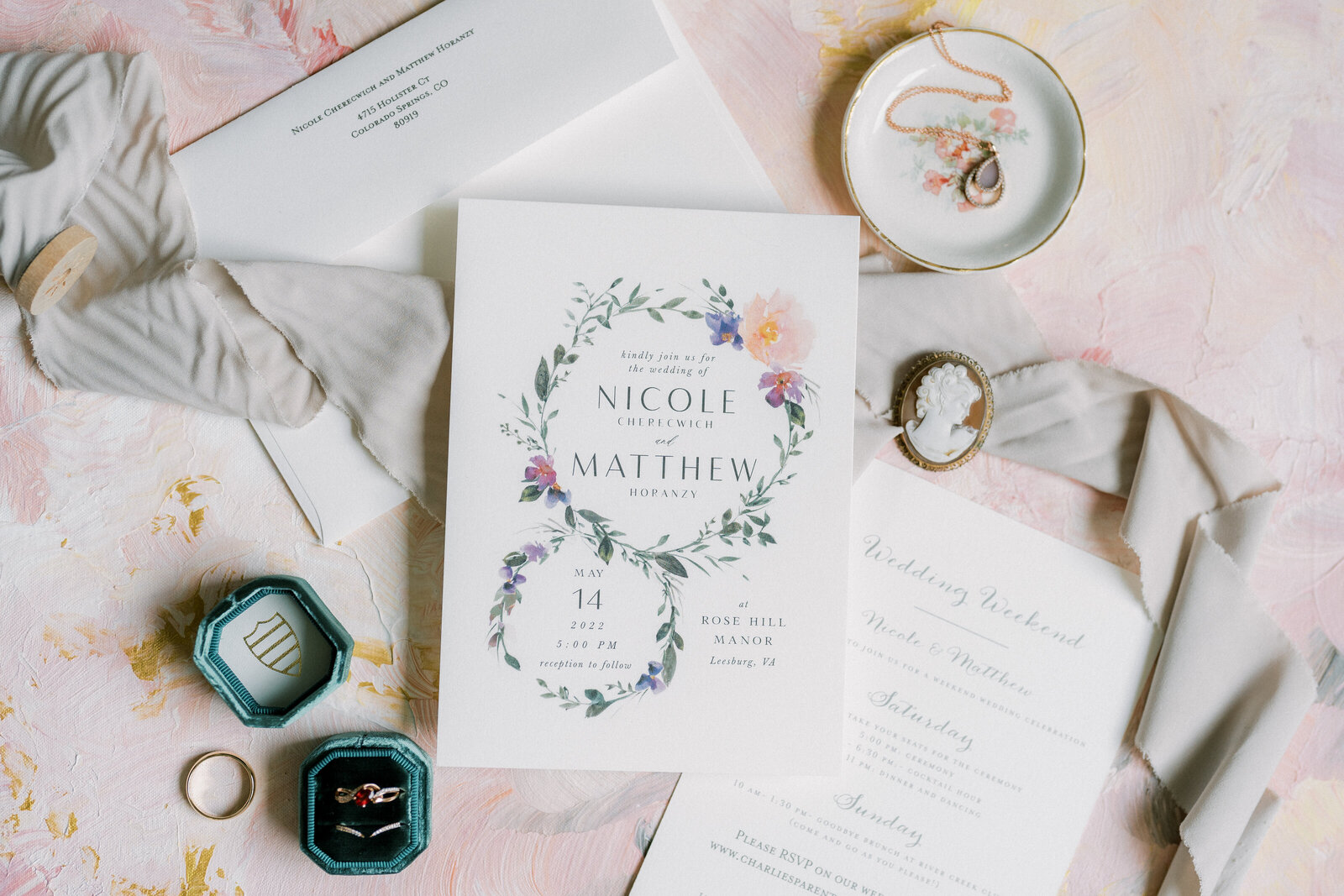 Wedding invitation and details on a pink backdrop