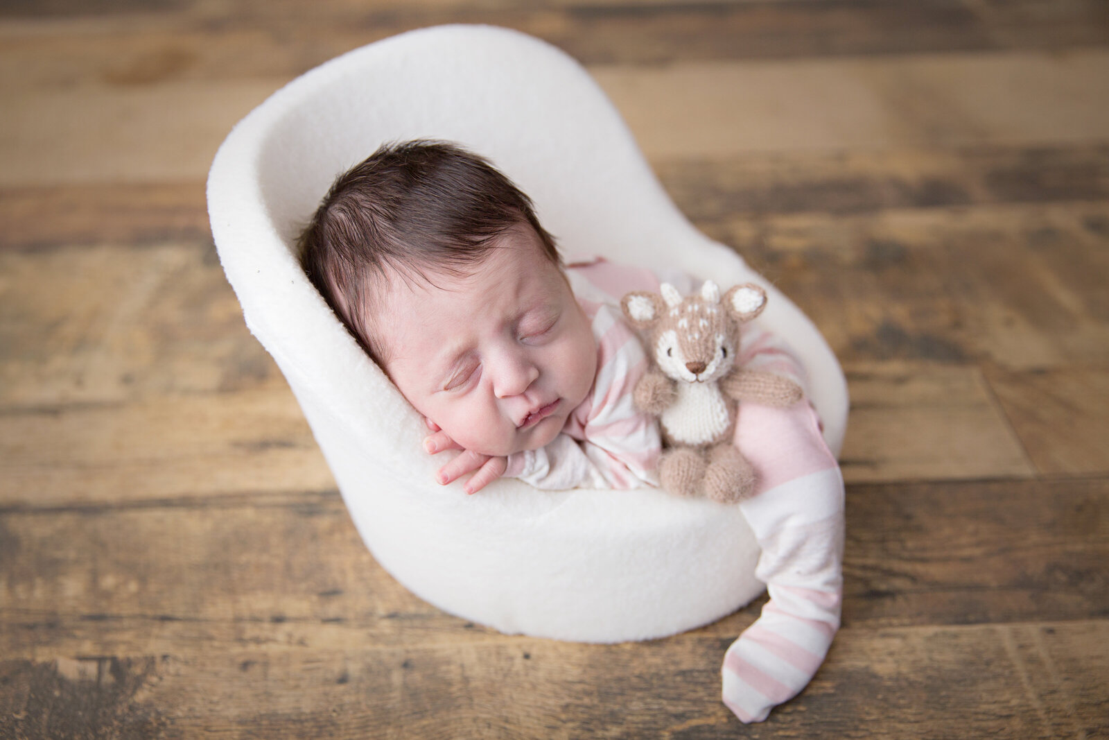 sleeping newborn baby with little teddy on posing pod