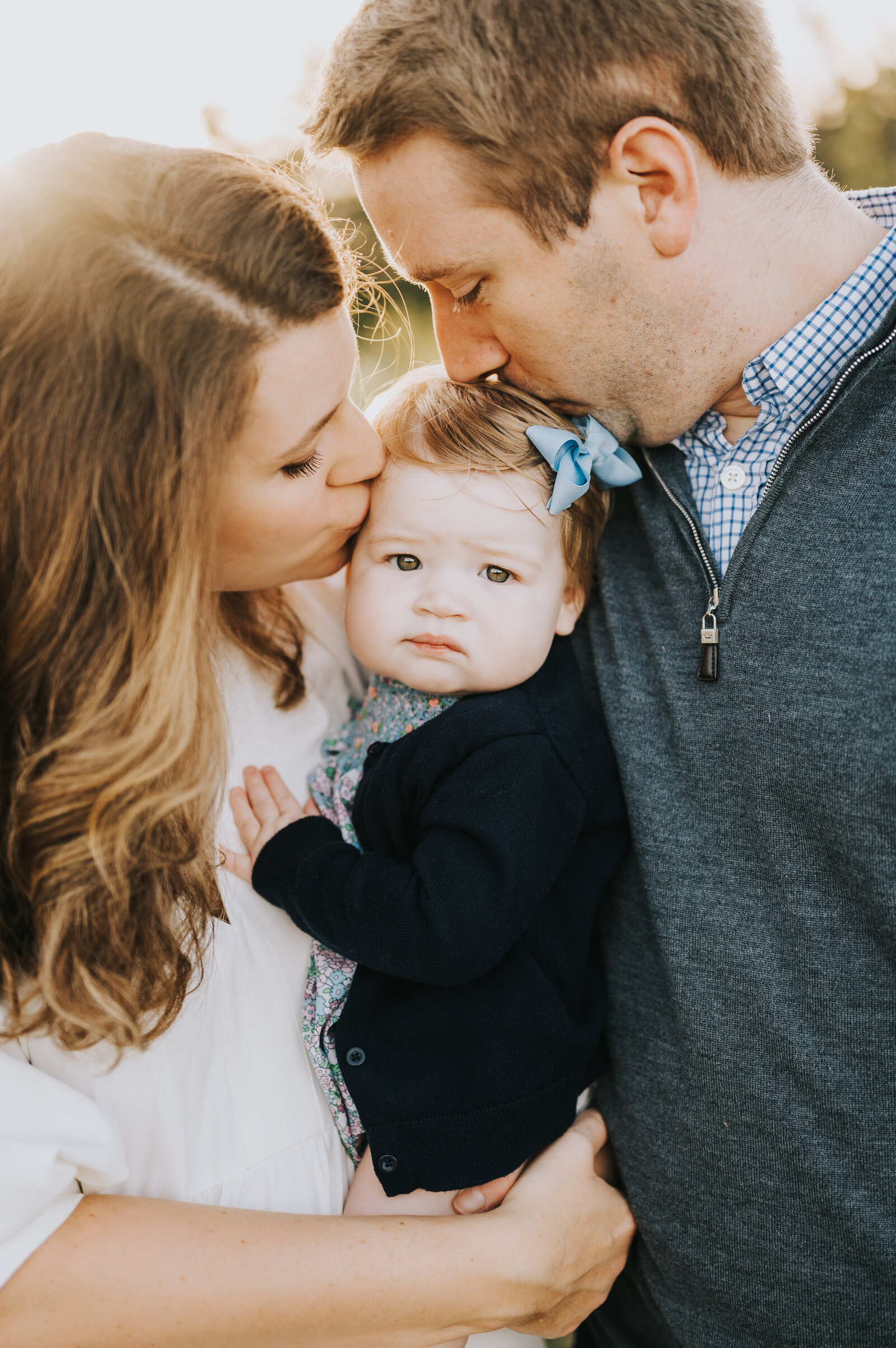 Couple holds and kisses baby girl during Fall family session in Raleigh, NC
