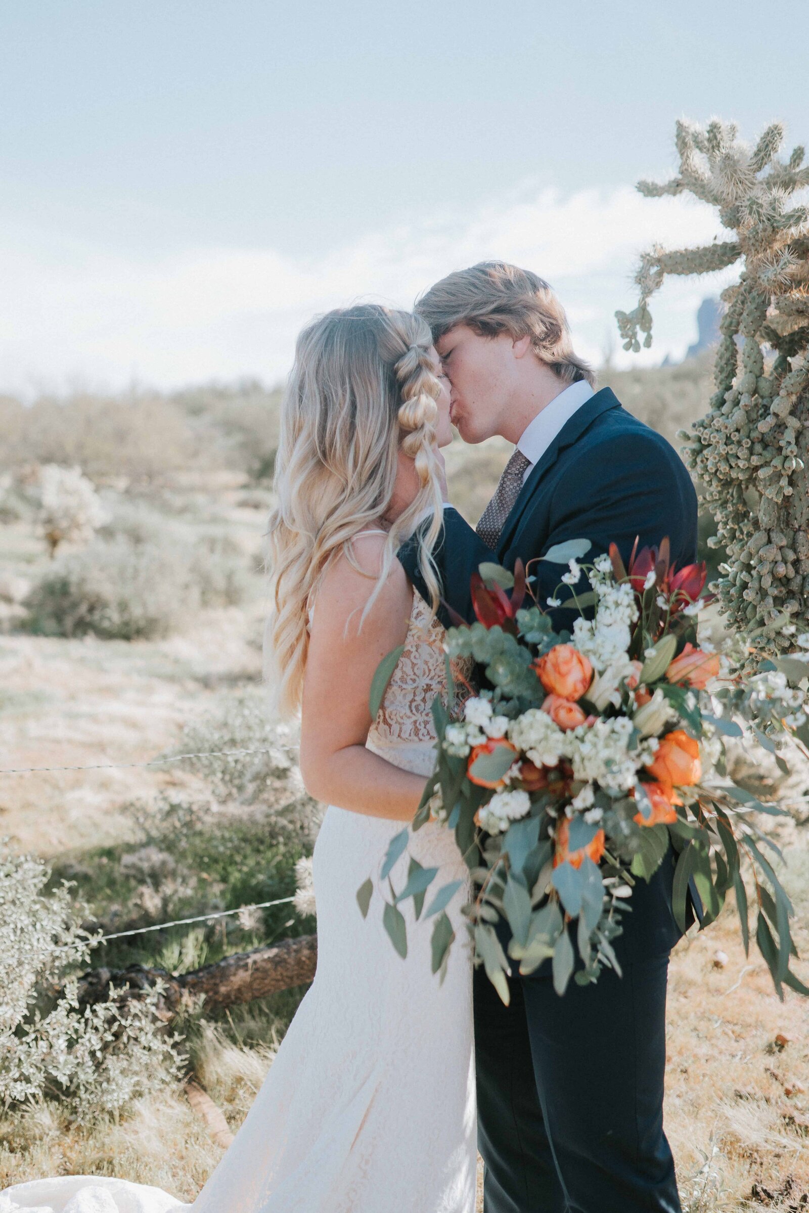 Sacramento Wedding Photographers capture bride and groom kissing while bride holds boho bouquet