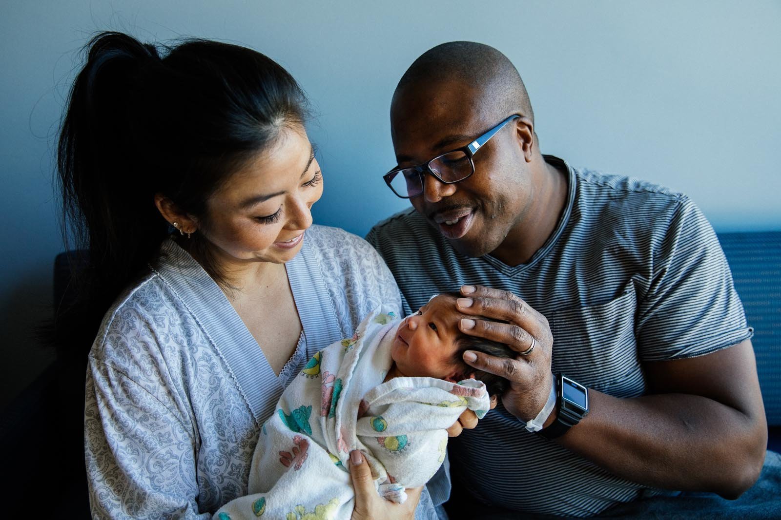 mixed couple in the hospital with newborn baby boy swaddled in a hospital blanket