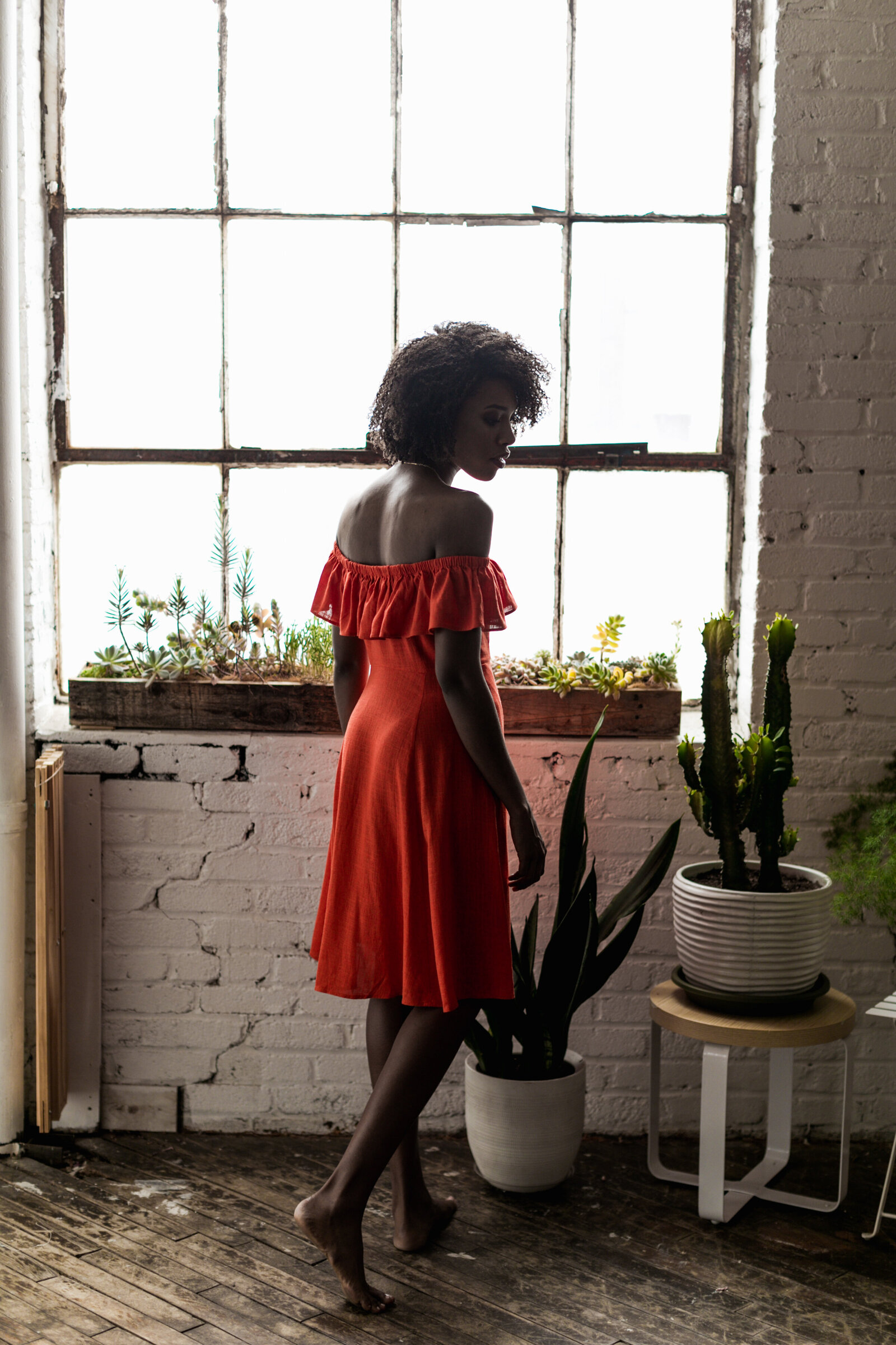 woman in red dress with plants and window