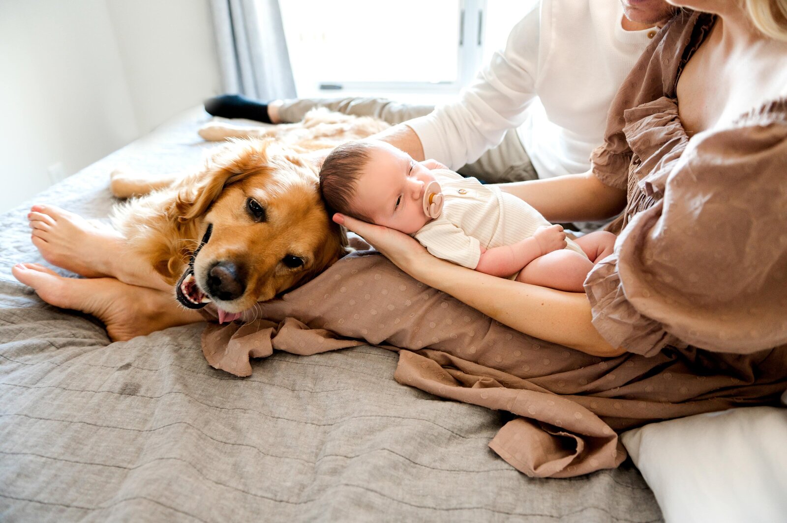 newborn boy and a  dog on a bed