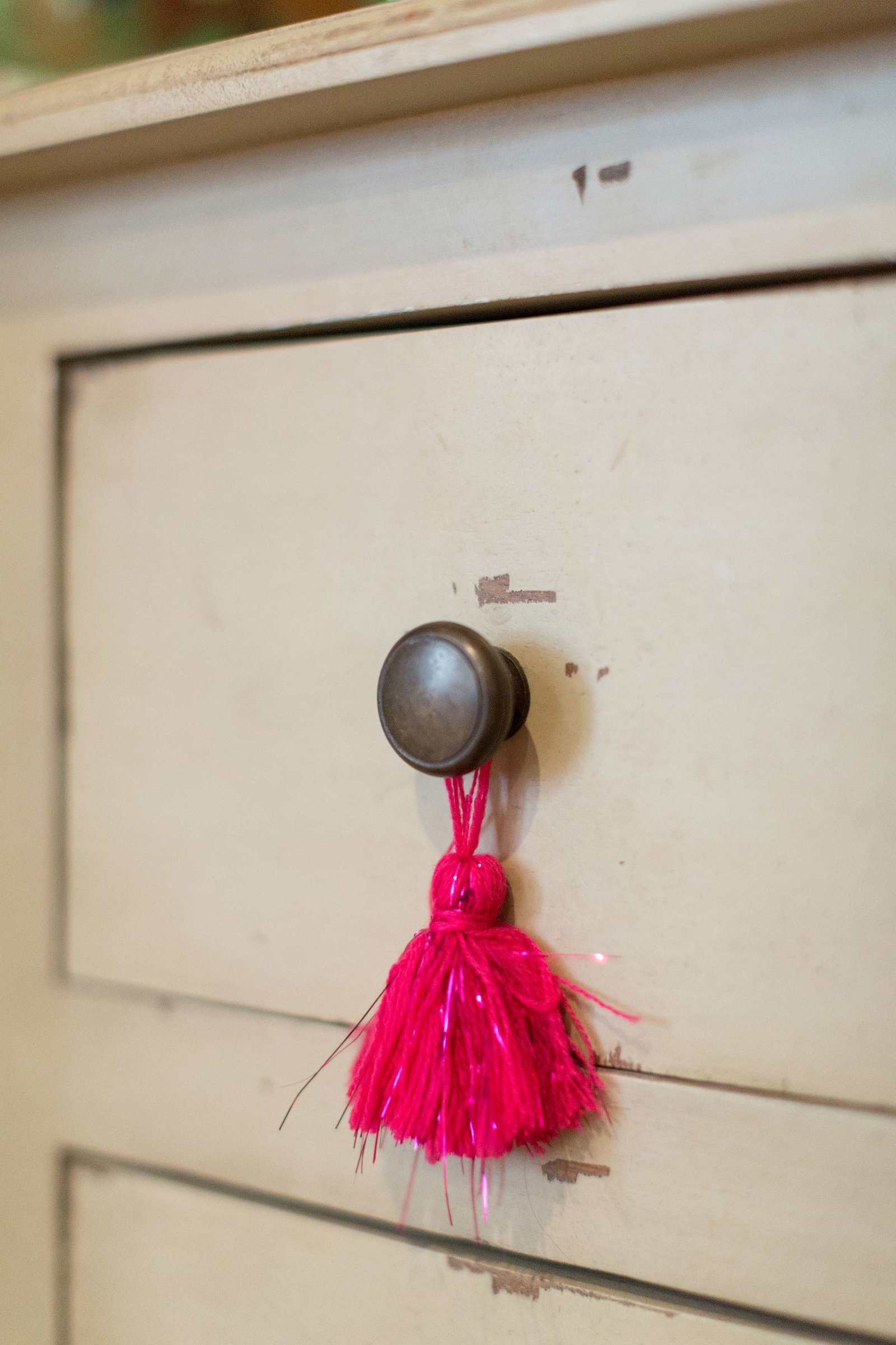 A drawer pull with hanging hot pink tassels.