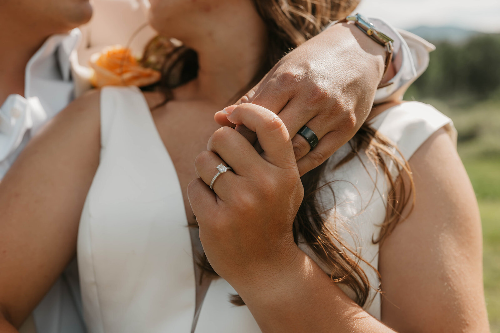 Close-up of a couple holding hands, showing wedding rings and part of their wedding attire outdoors—captured by a Colorado elopement photographer capturing real connection.