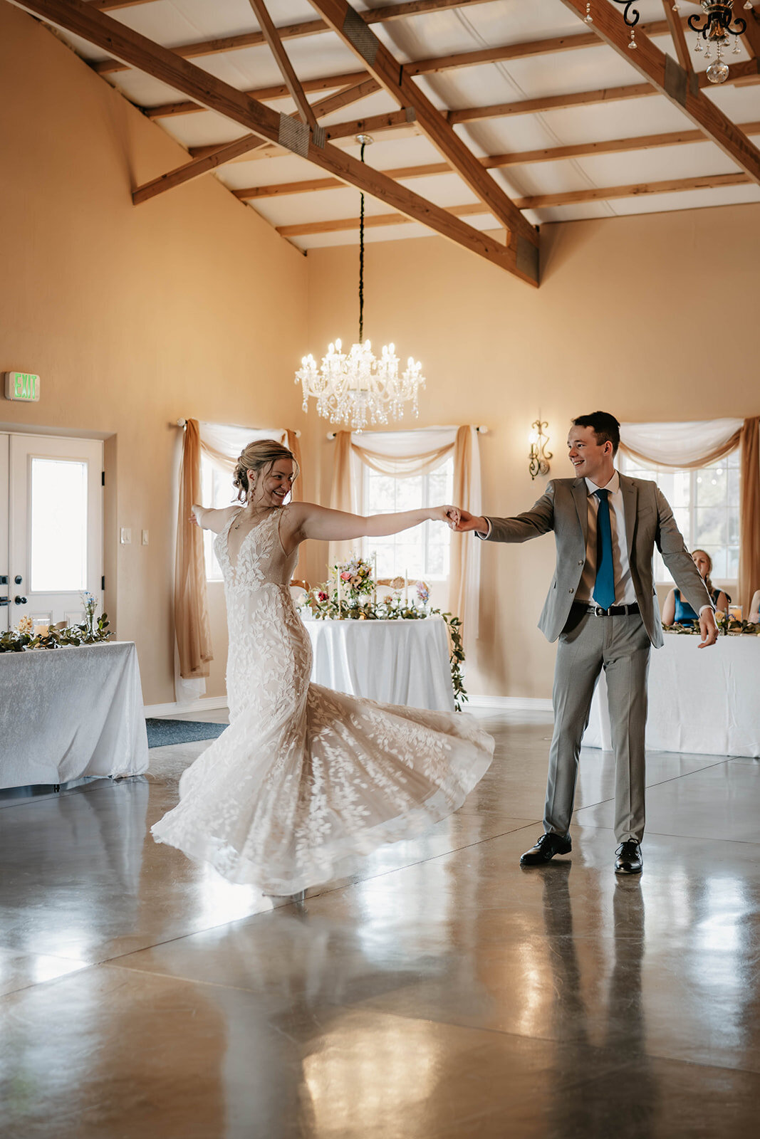 A bride and groom dance together in a bright, elegant wedding reception hall as their Colorado elopement photographer capturing real connection immortalizes the joy of their special day.