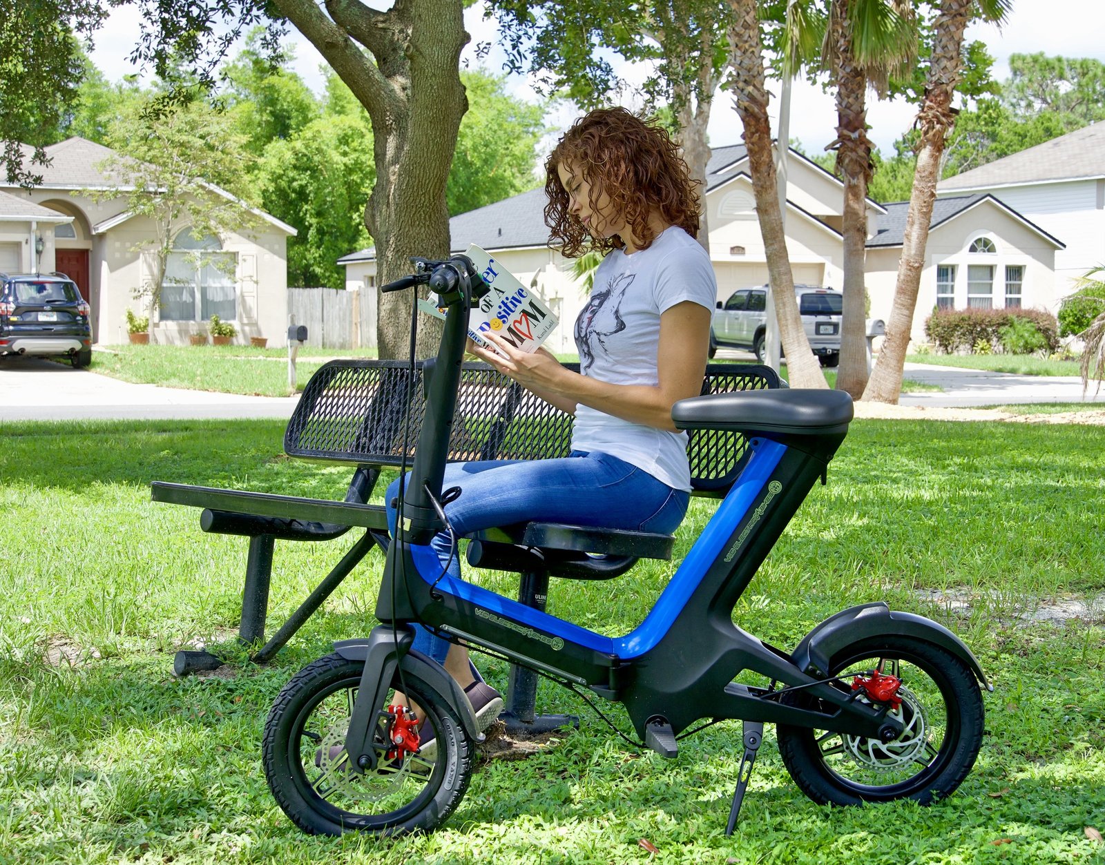 Women sitting on a bench at the park while reading a book demonstrating a Blue Go-Bike M3