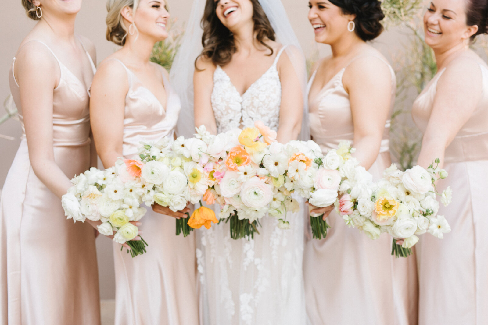 Bride and bridesmaids with matching bouquets and cream dresses.