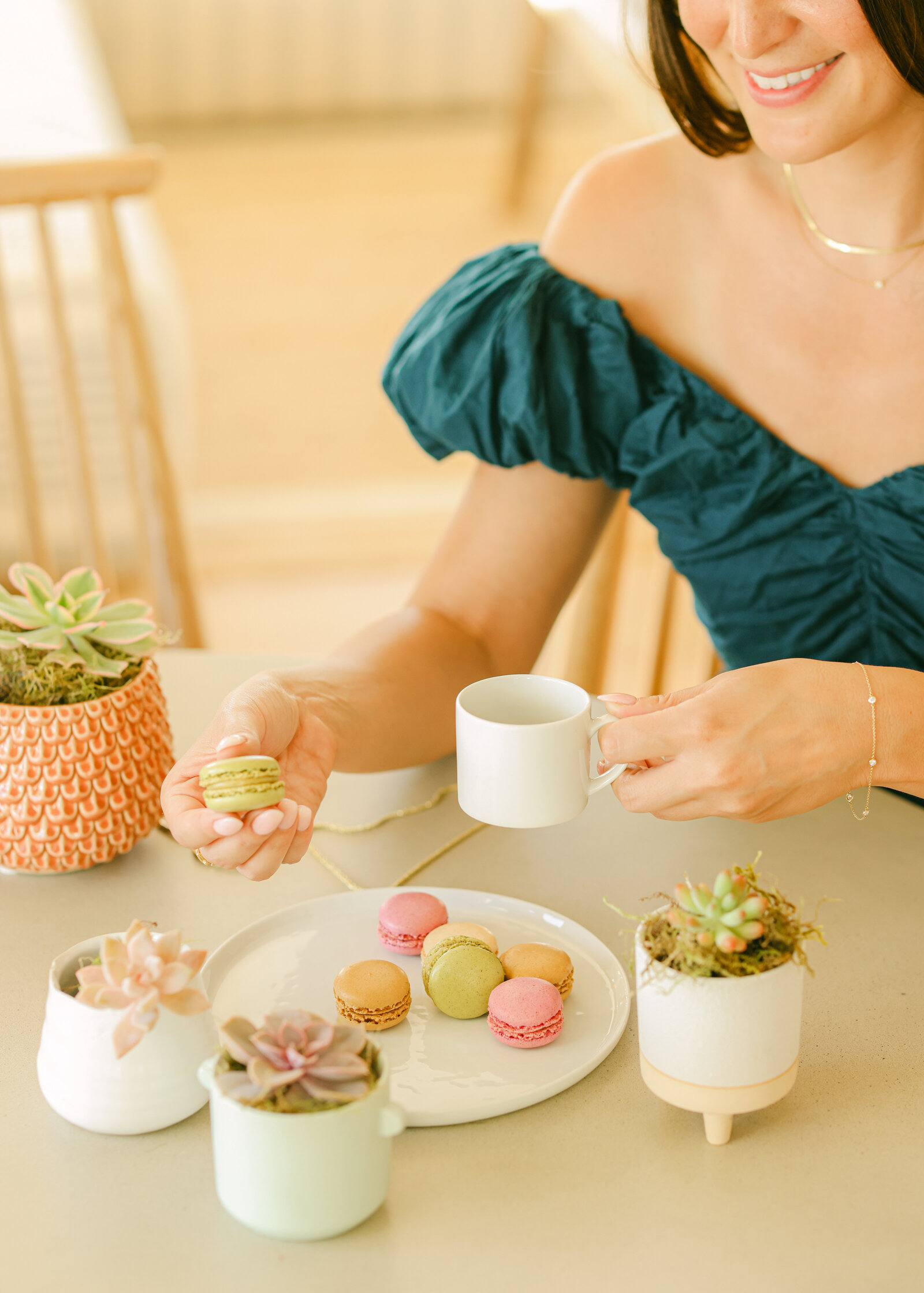 fashionable girl eating macarons at a table surrounded by succulents