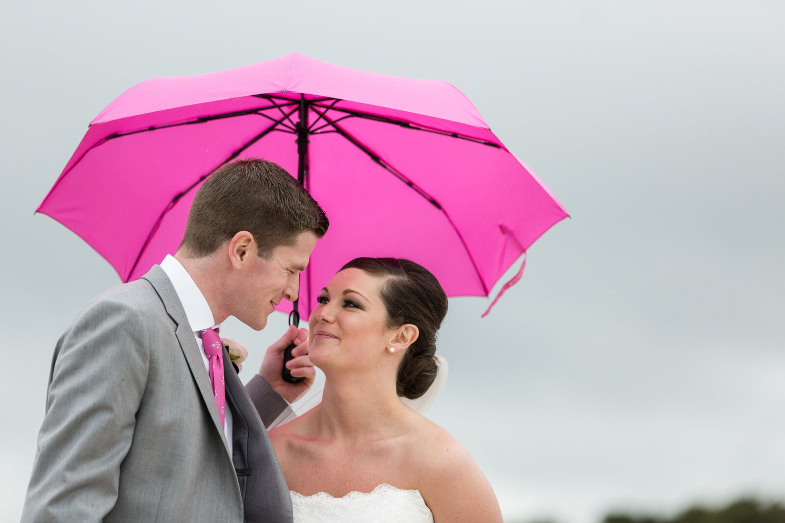 bride and groom under pink umbrella