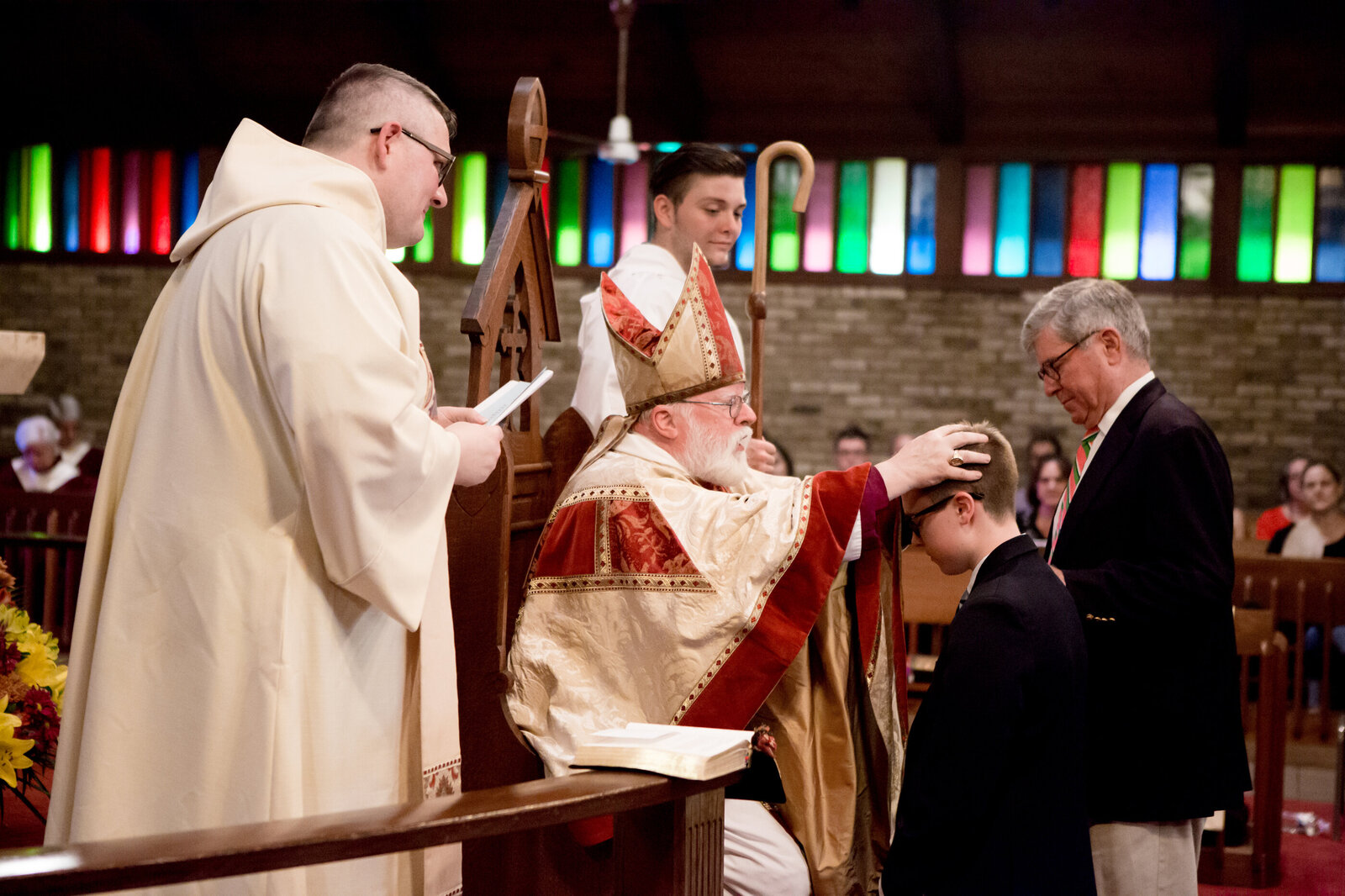 Bishop blesses teenage boy while sponsor and two priests look on Saint Augustine New City Rockland County confirmation photographer Milestone Images