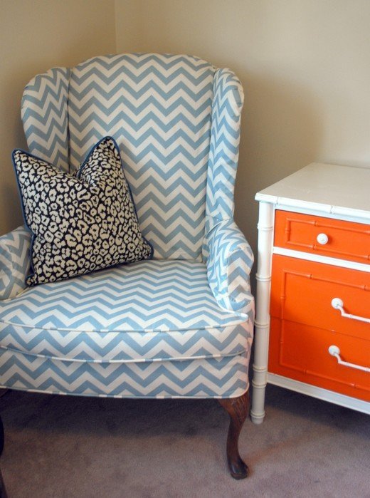 A blue and white chevron chair beside an orange and white dresser.