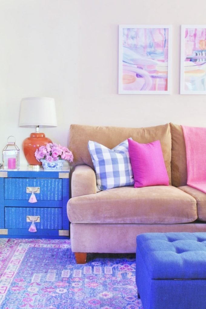 A tan sofa, blue wicker end table, and blue tufted ottoman.