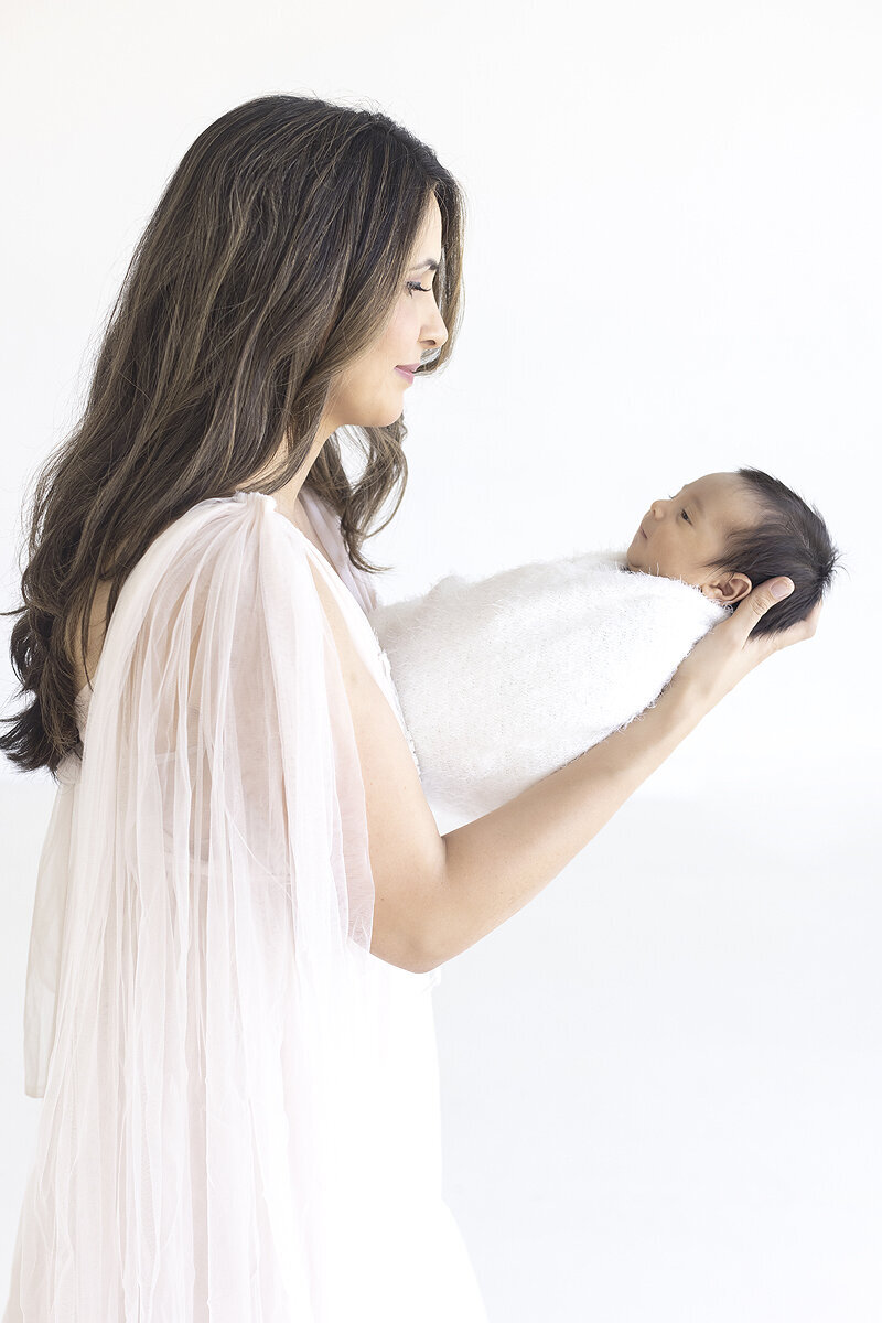 New mother holding newborn son, a Dallas newborn photographer.