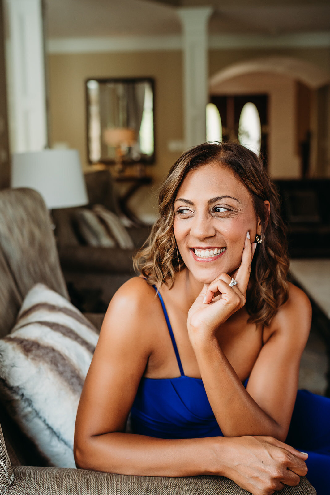 woman smiles while relaxing on a couch during brand photo session