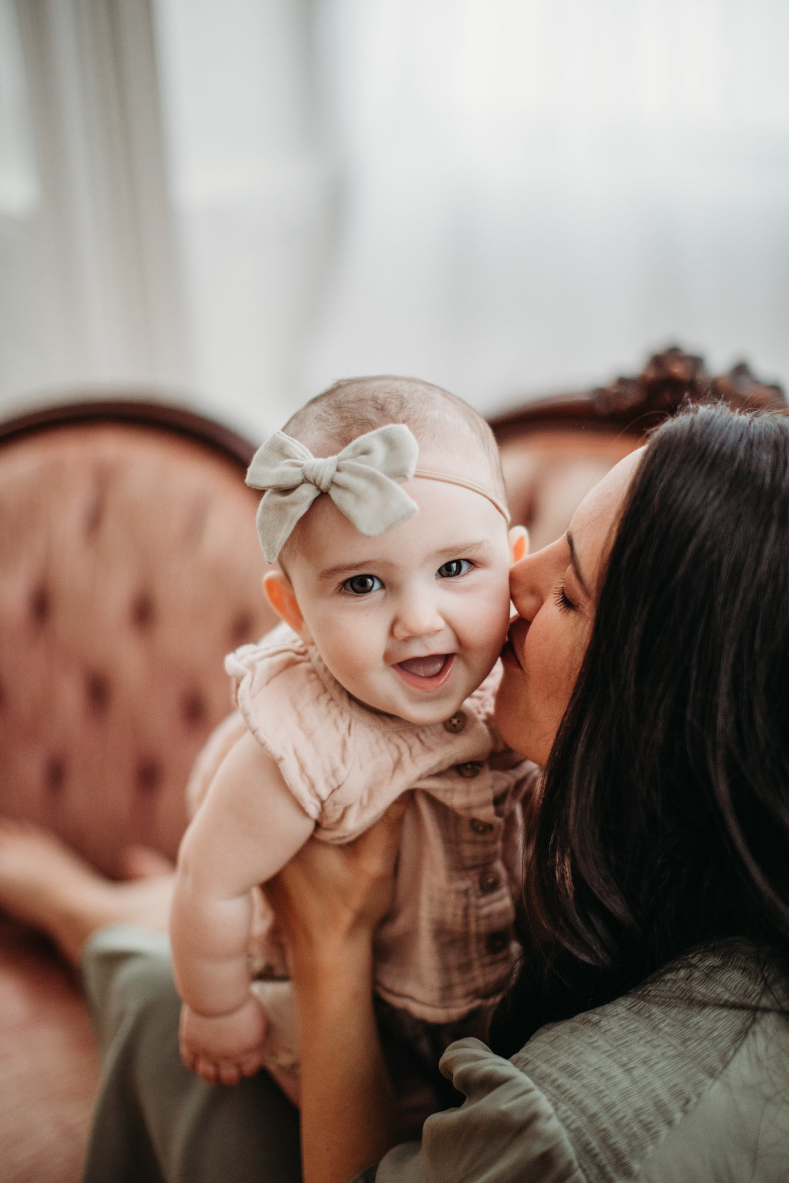mom kisses daughter with bow