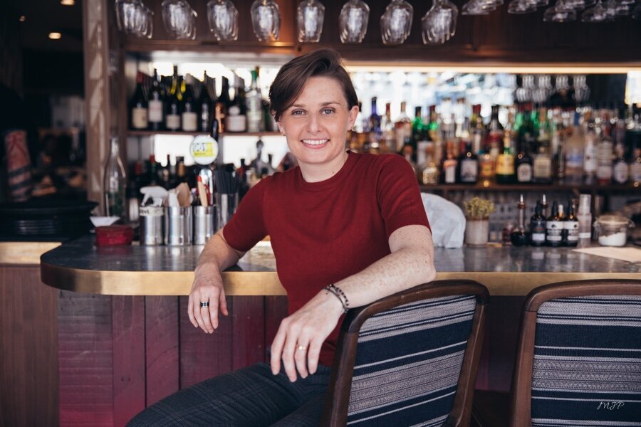 Portrait of restaurateur in front of their bar