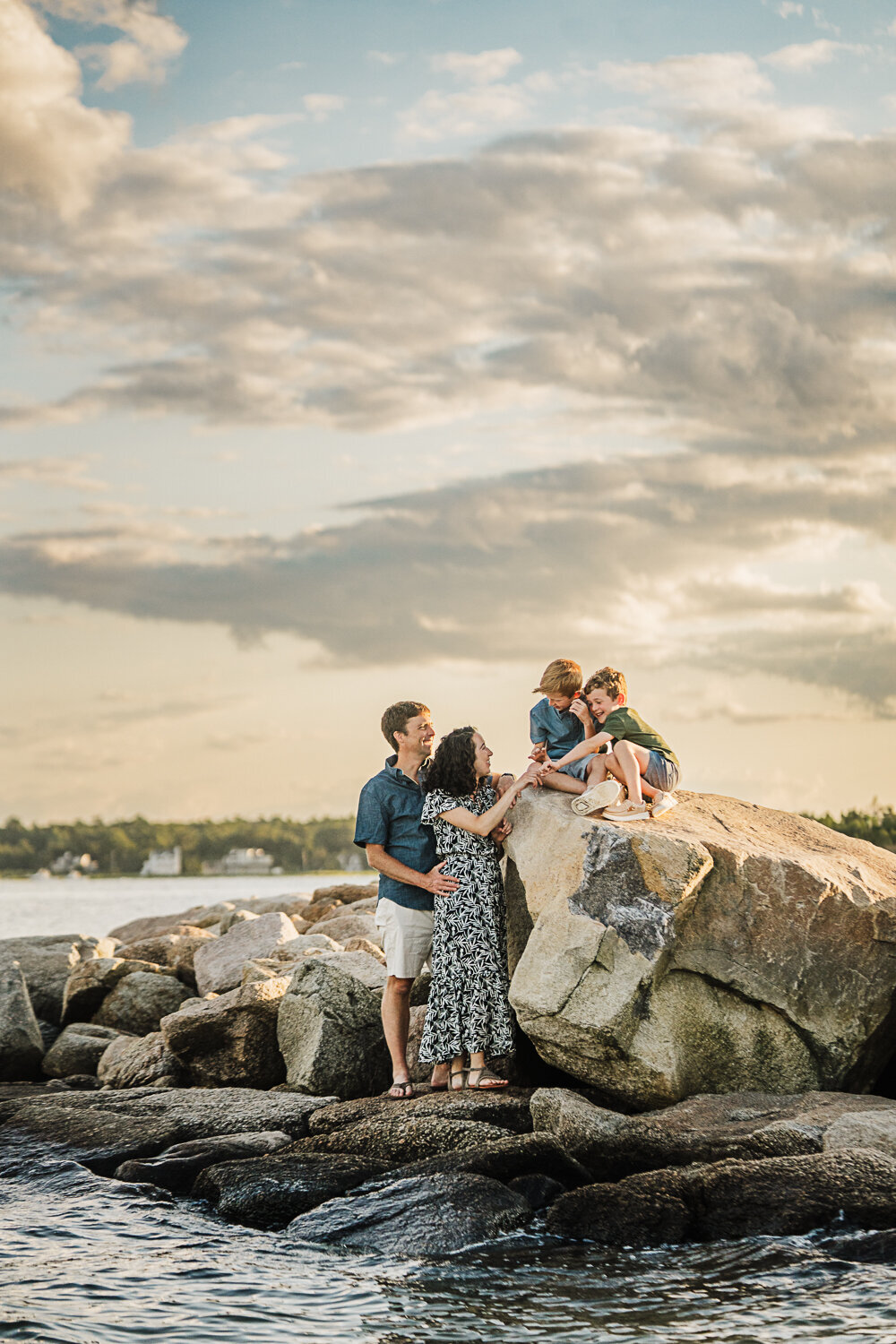 family of four climb on rocks near ocean