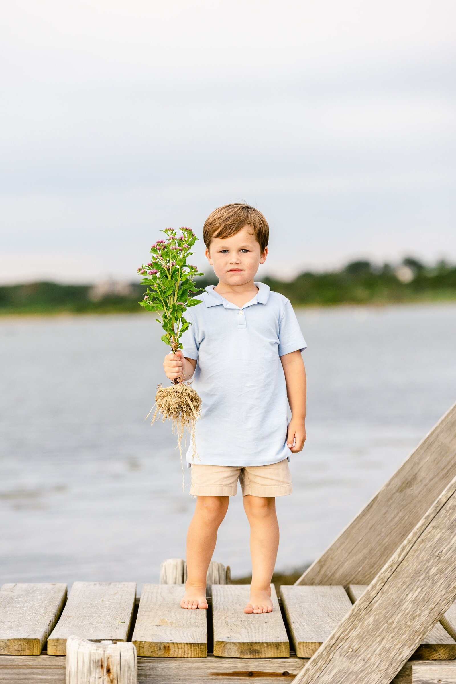 boy holding flowers on dock