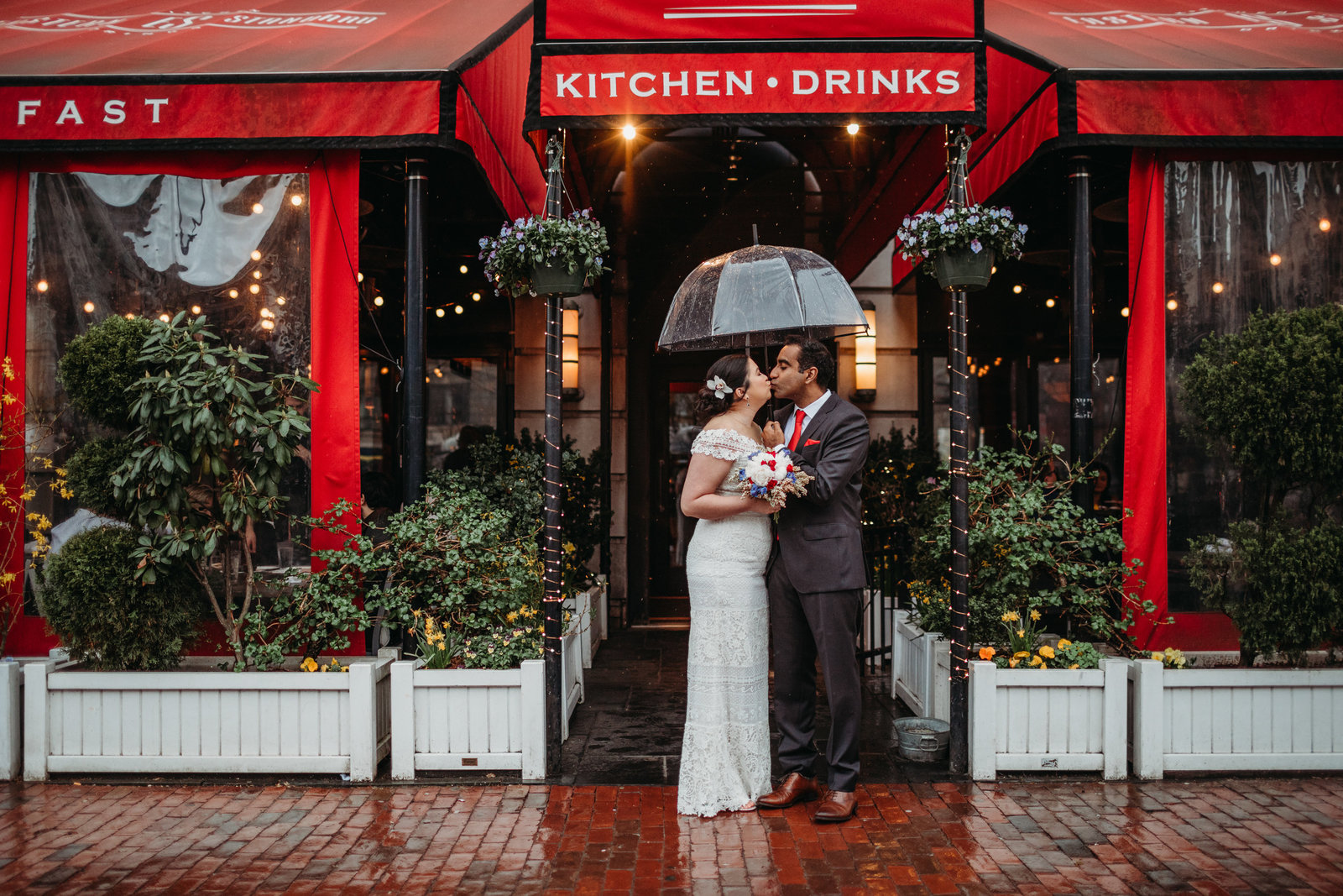 couple stands under an umbrella in the rain after eloping