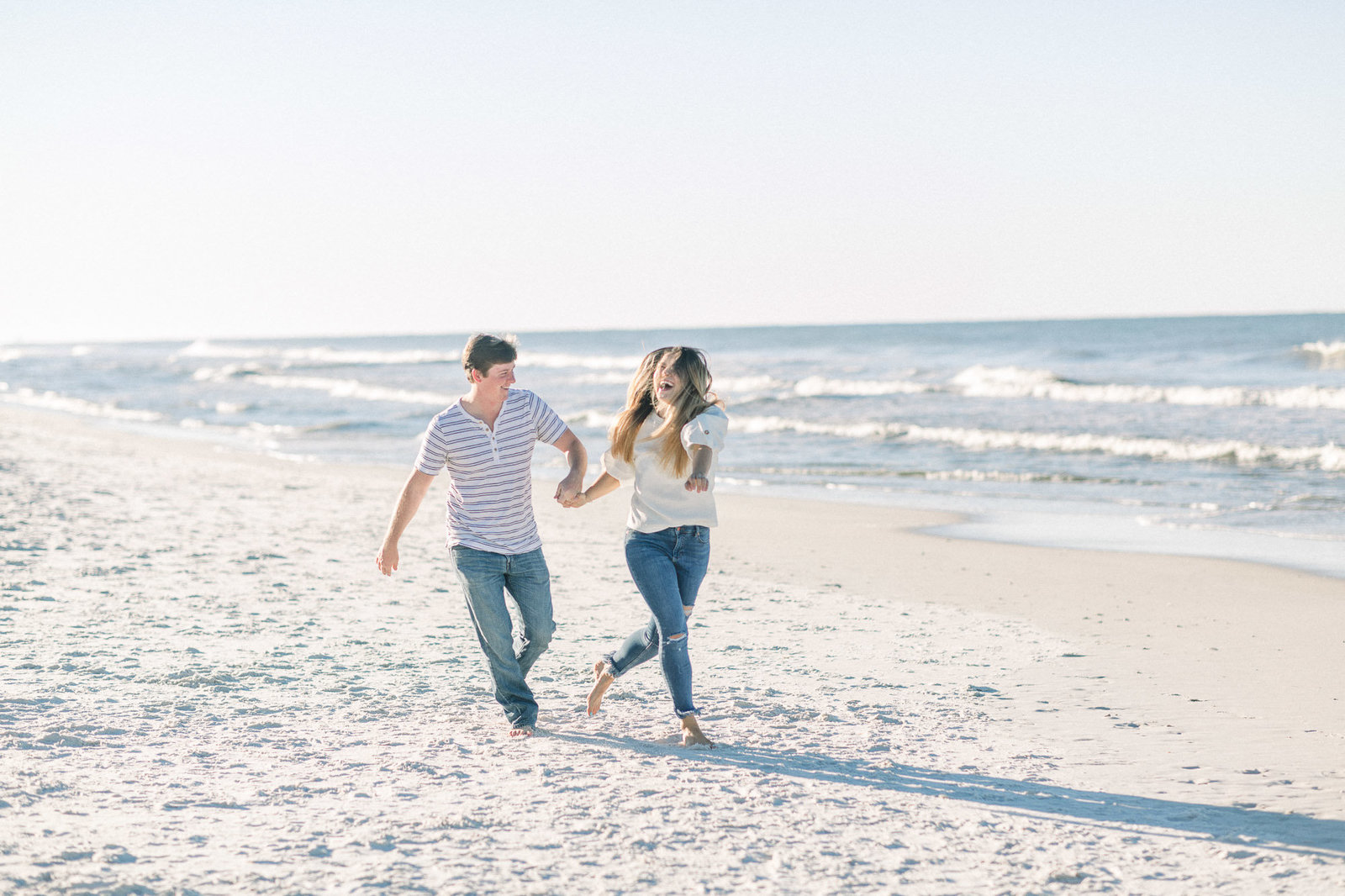 Couple running on the beach captured by Staci Addison Photography