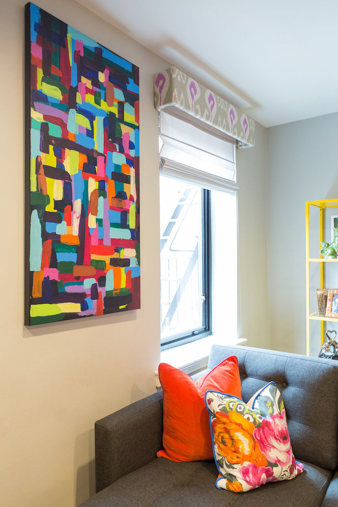 A colorful abstract painting hung above a gray sectional.
