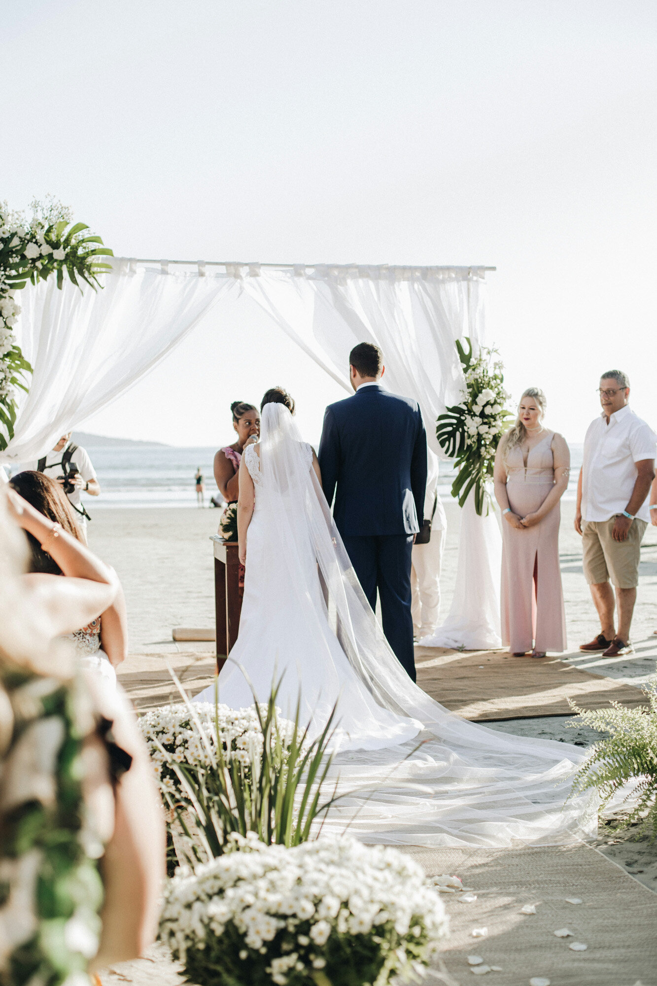 Beach wedding ceremony, the bride and the groom with the officiant