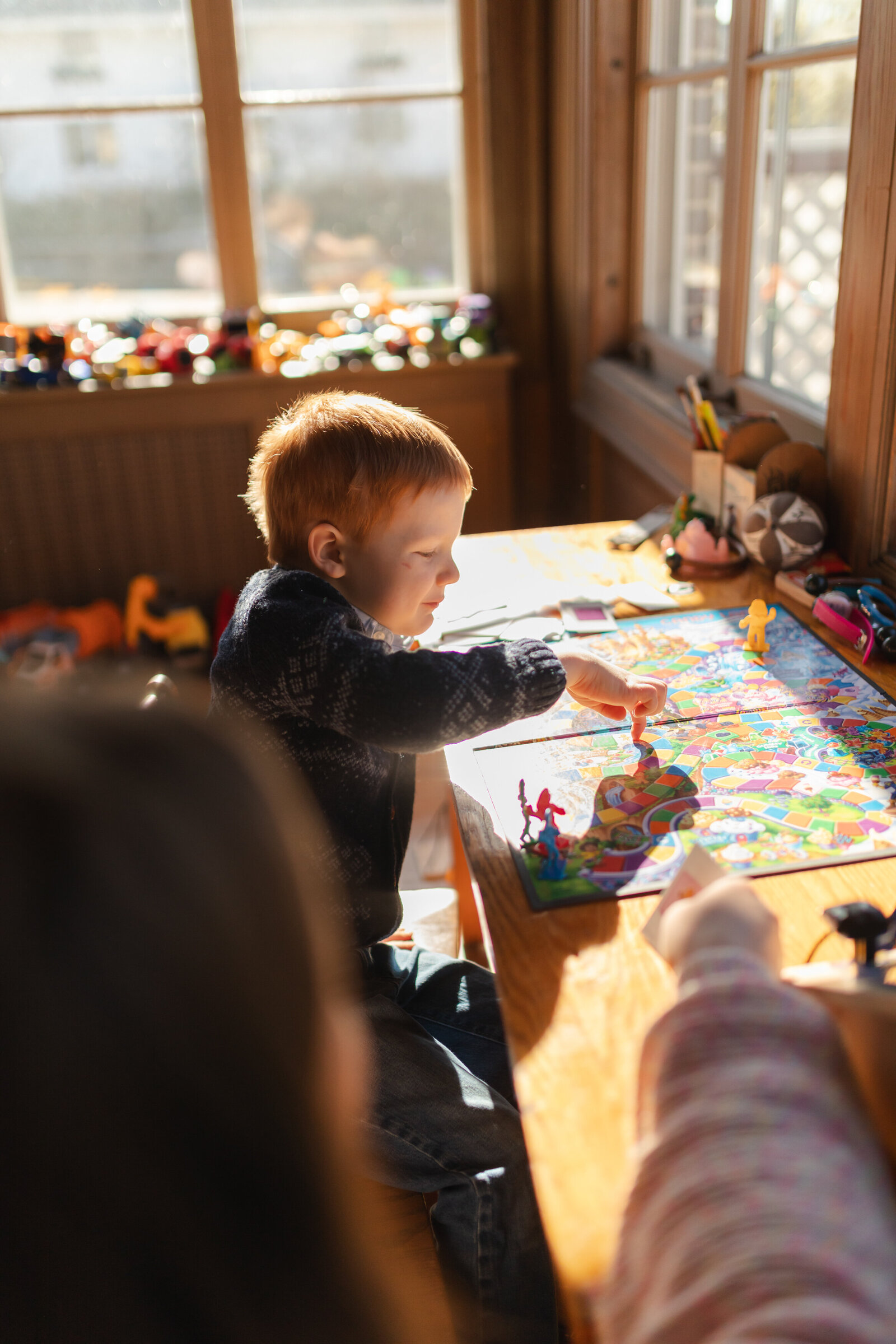 young boy and mother play candyland in sun filled playroom