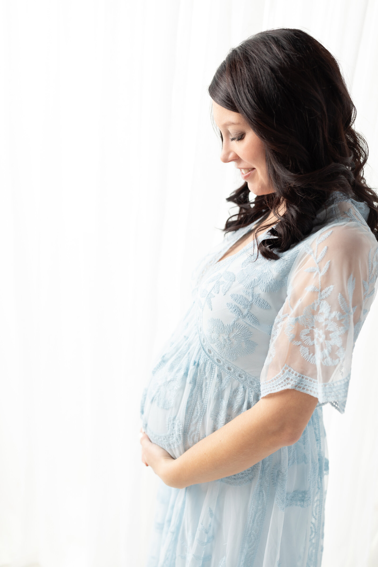 pregnant mother in blue dress holding belly for photoshoot