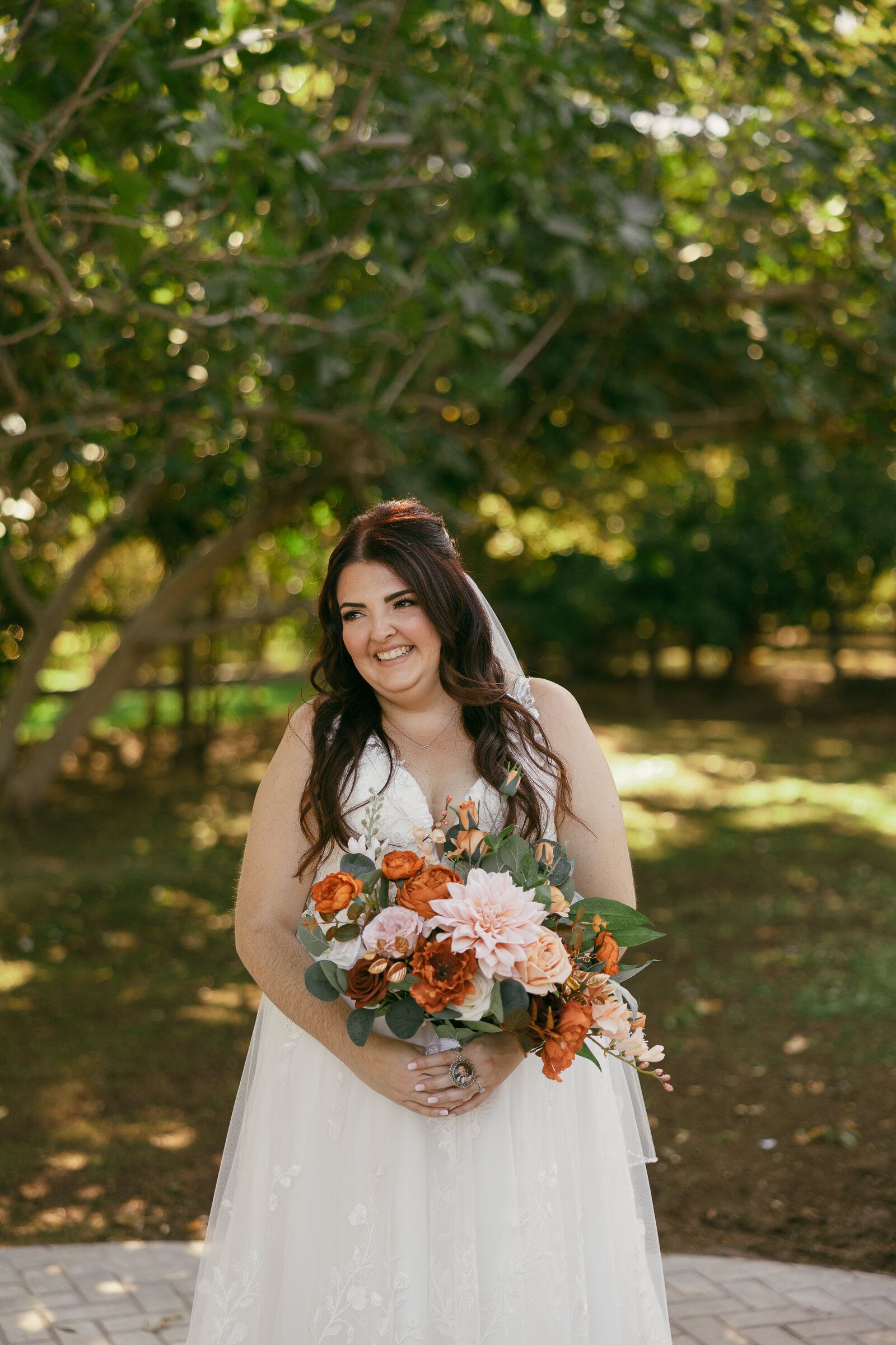 A bride smiling while holding a bouquet of flowers.