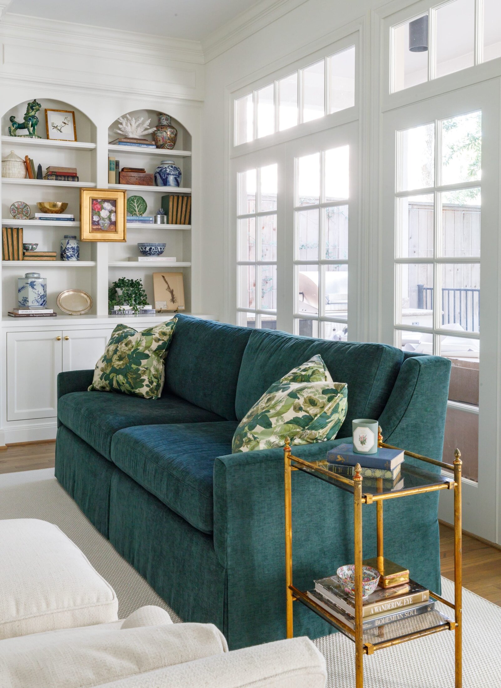vision and hammer living room with styled shelf and green sofa with gold accent side table