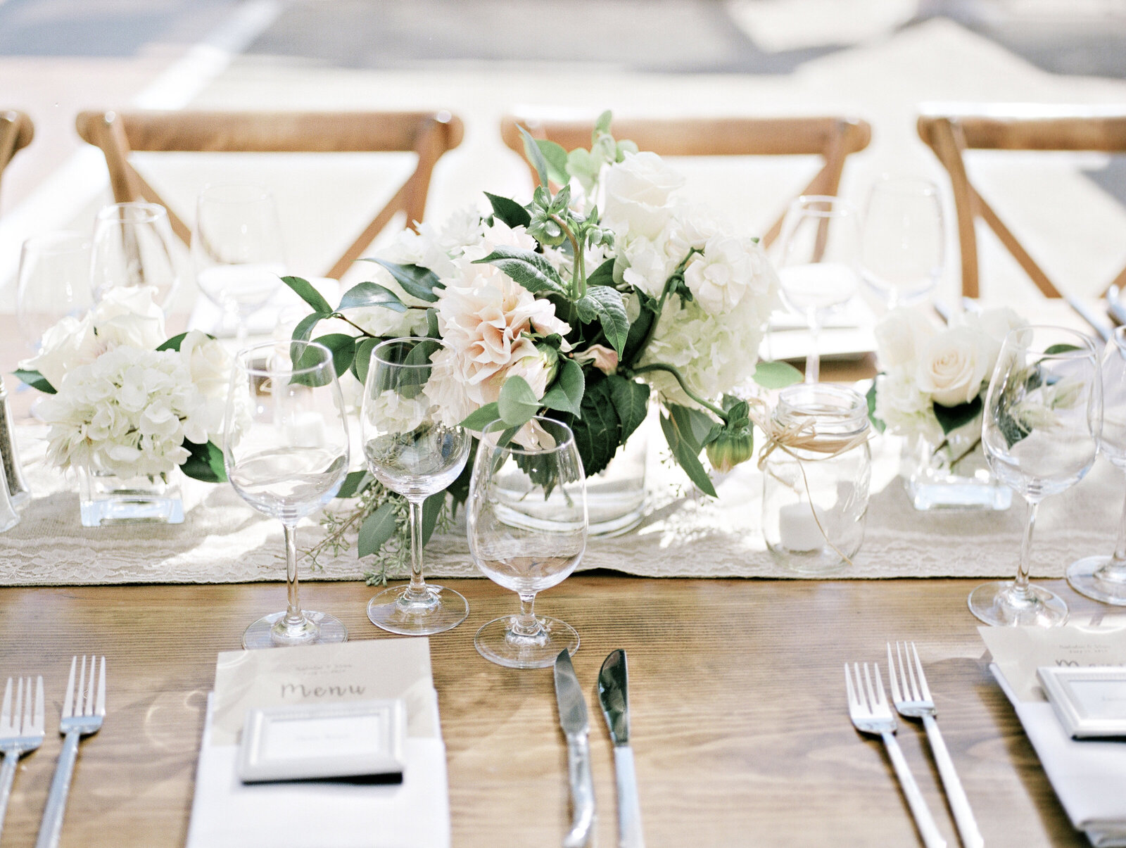Wedding table place settings with greenery, flowers and glassware