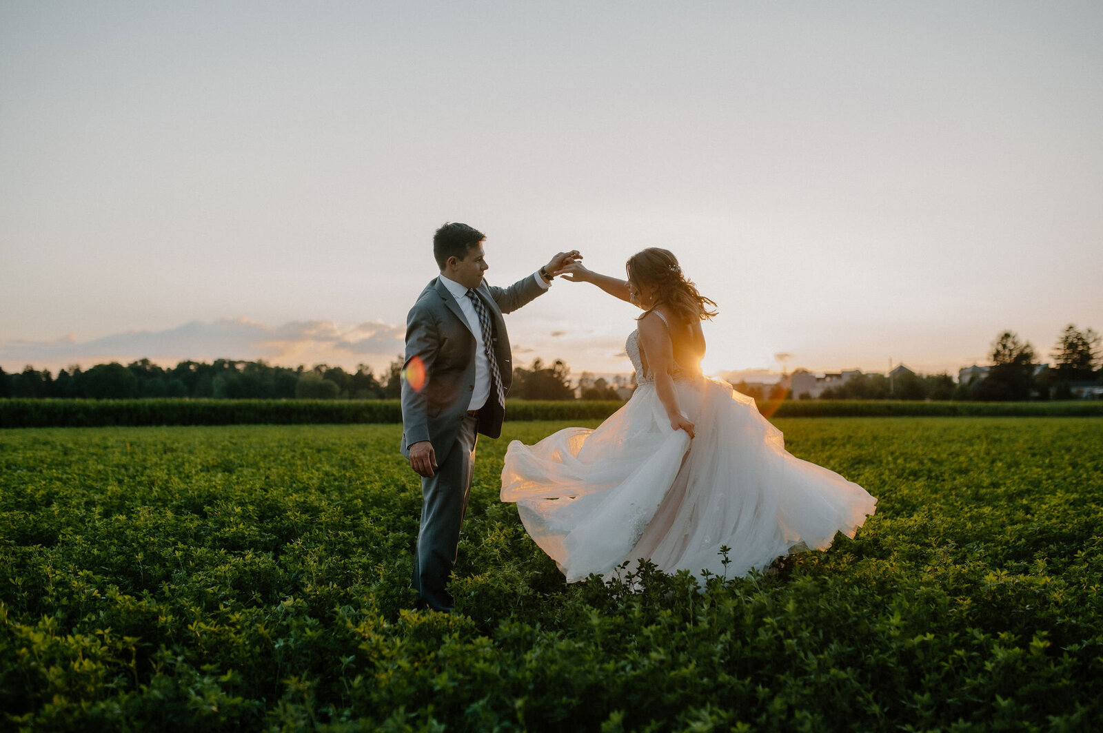 couple twirling in lush field at golden hour at The Barn at Silverstone wedding