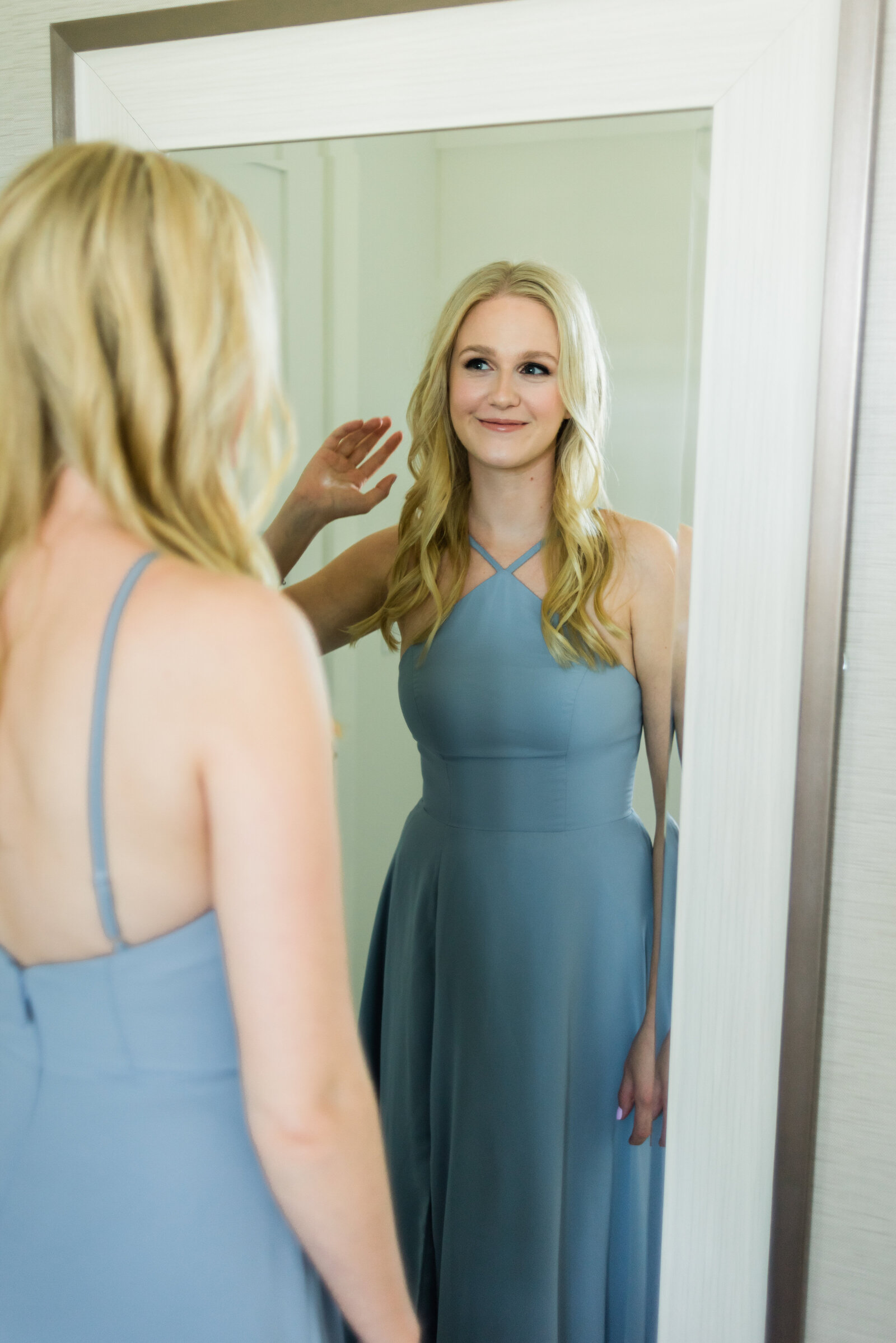 Bridesmaid in blue dress looking in a mirror