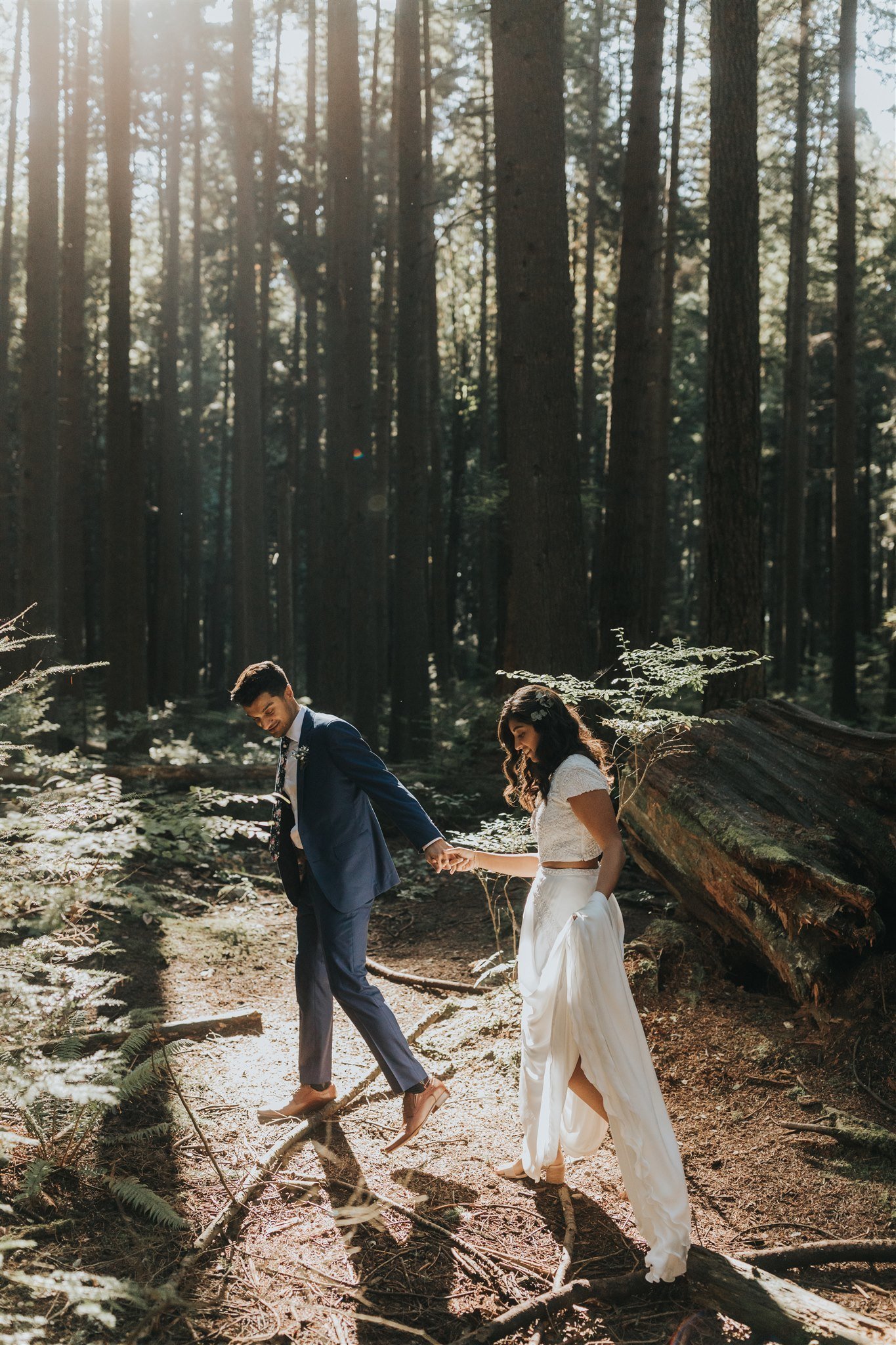 bride and groom walking through magical forest light