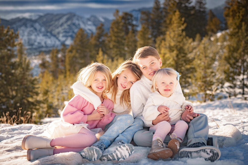 four kids give each other hugs on the snow