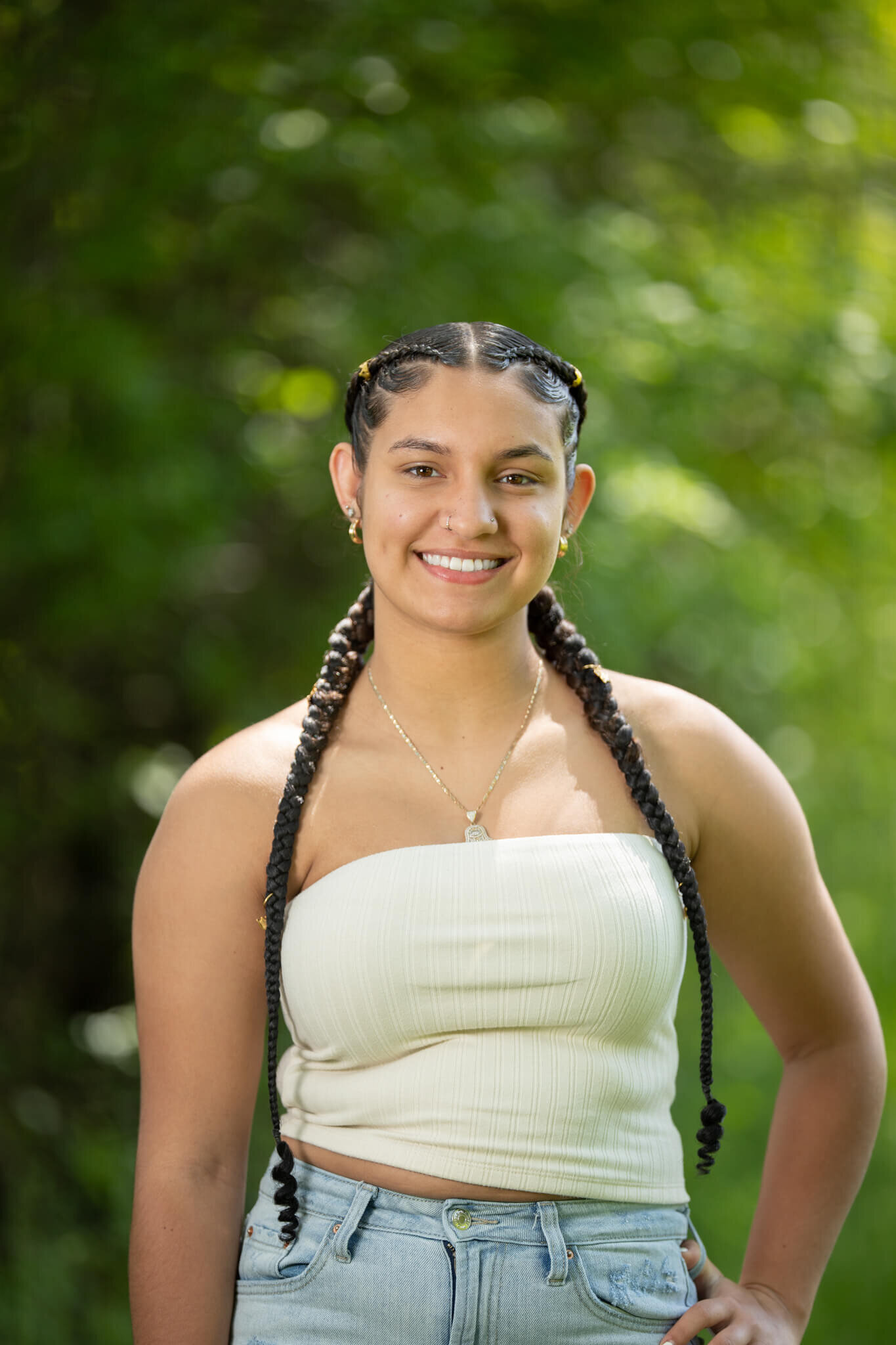 High school senior portrait photography in Clinton MA  of female in a white top smiling at the camera with a green and yellow background and one hand on her hip while standing